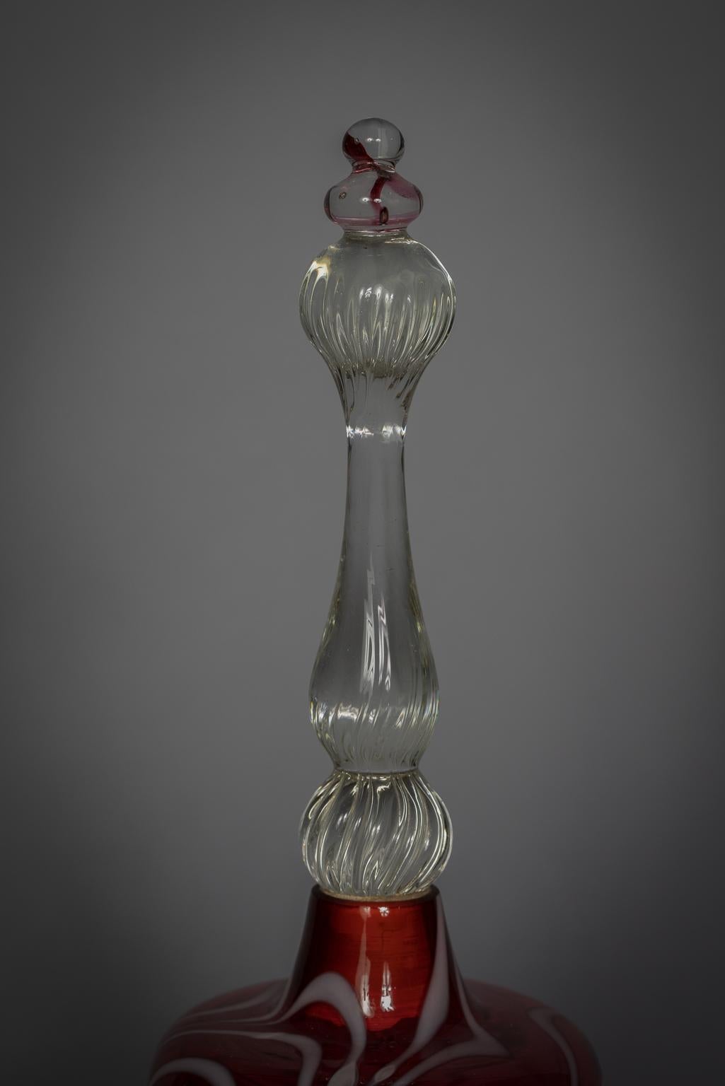 grande cloche rouge avec décoration blanche en forme de peigne et poignée transparente avec claquement en verre transparent.