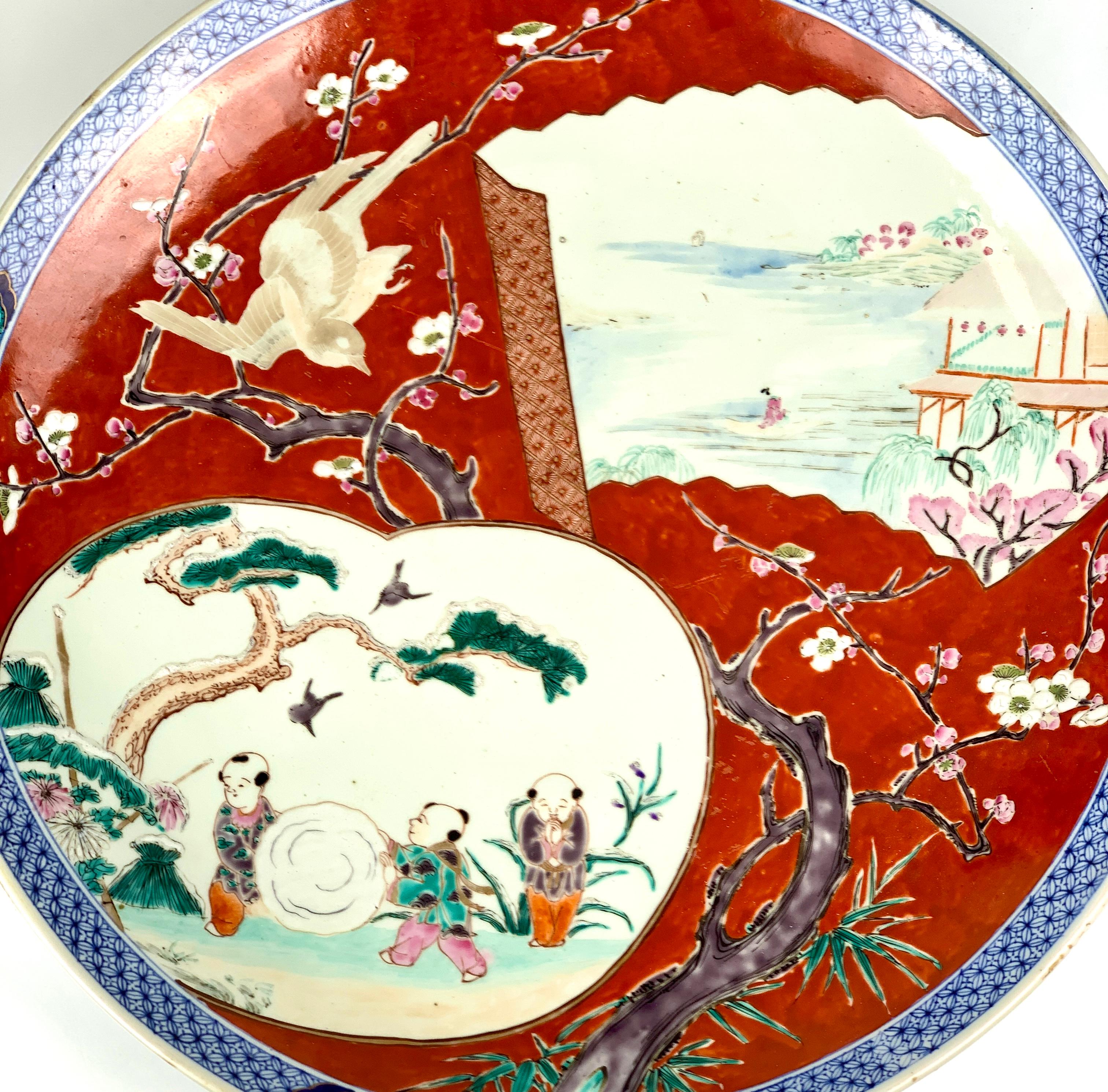 This large antique charger (18 inches in diameter) is a showpiece of Japanese decorative art. 
Made in the late 19th-century Meiji period, the intricate hand-painted design shows a delightful depiction of children at play in the snow, a charming