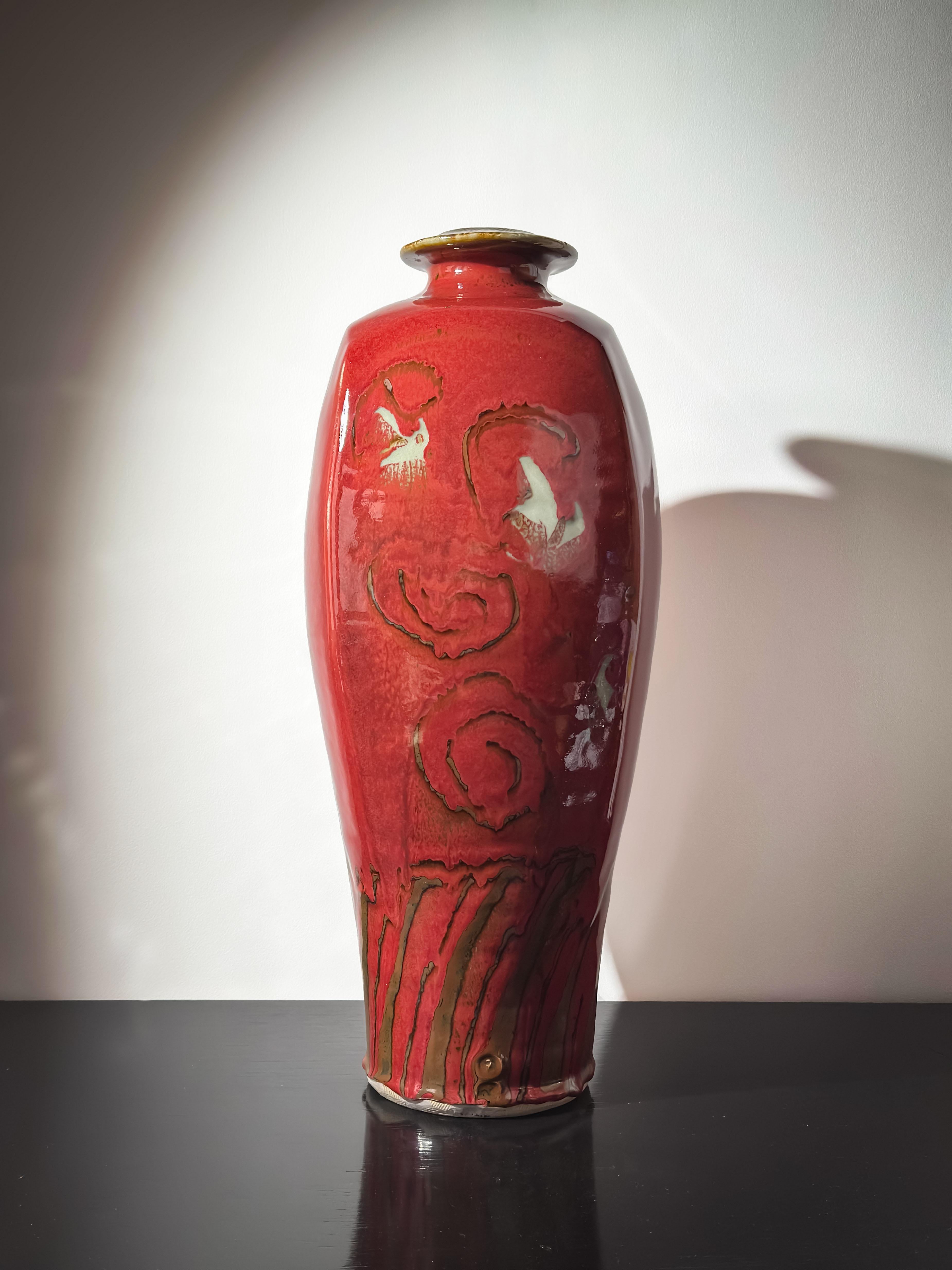 This large red glazed ceramic vase, hand-thrown by British studio potter David Frith at Brookhouse Pottery circa 1980s, is a striking example of modernist studio pottery with pronounced East Asian influences. Its tall, architectural form—a