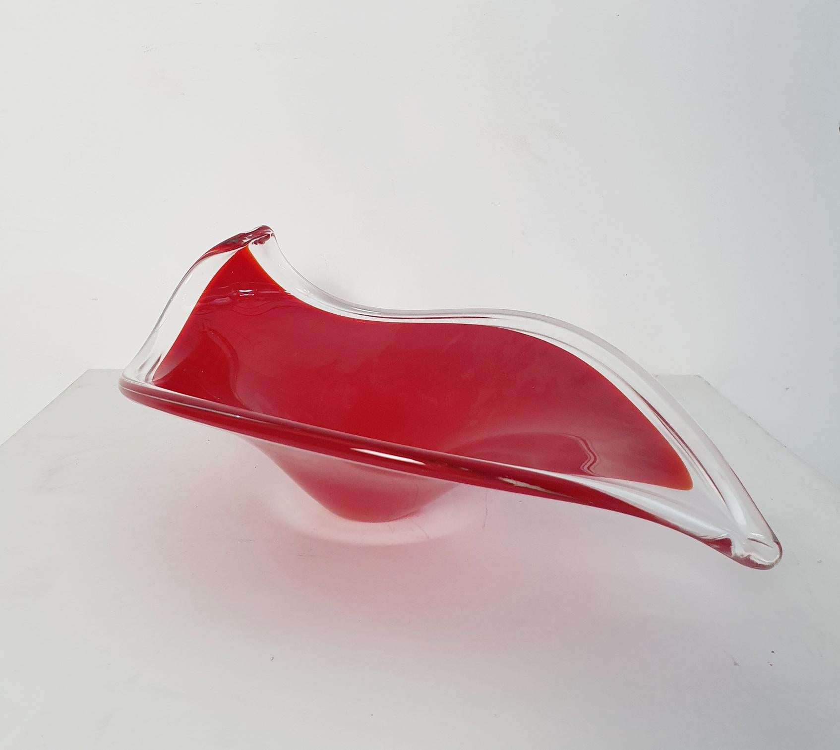 Décoratif et méticuleusement réalisé en verre de Murano, ce bol présente une forme de feuille caractéristique et un poids substantiel. Le jeu du verre rouge et du verre transparent forme un mélange harmonieux, façonné à la main de manière experte.