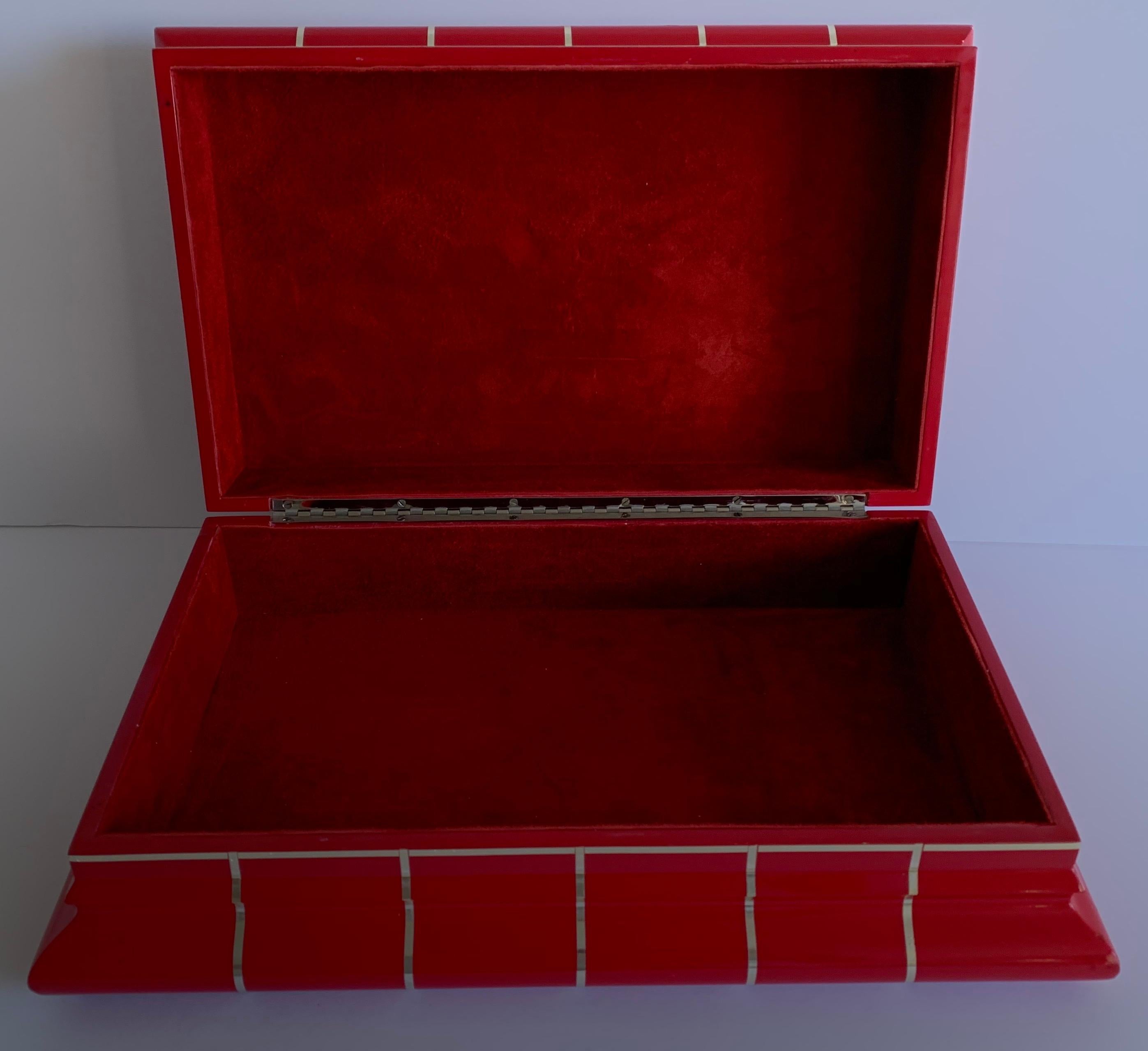 Large red lacquer box attributed to Karl Springer. Inset polished brass trim in a geometric design. Lined in red suede. Hinge style attached lid. No makers mark.