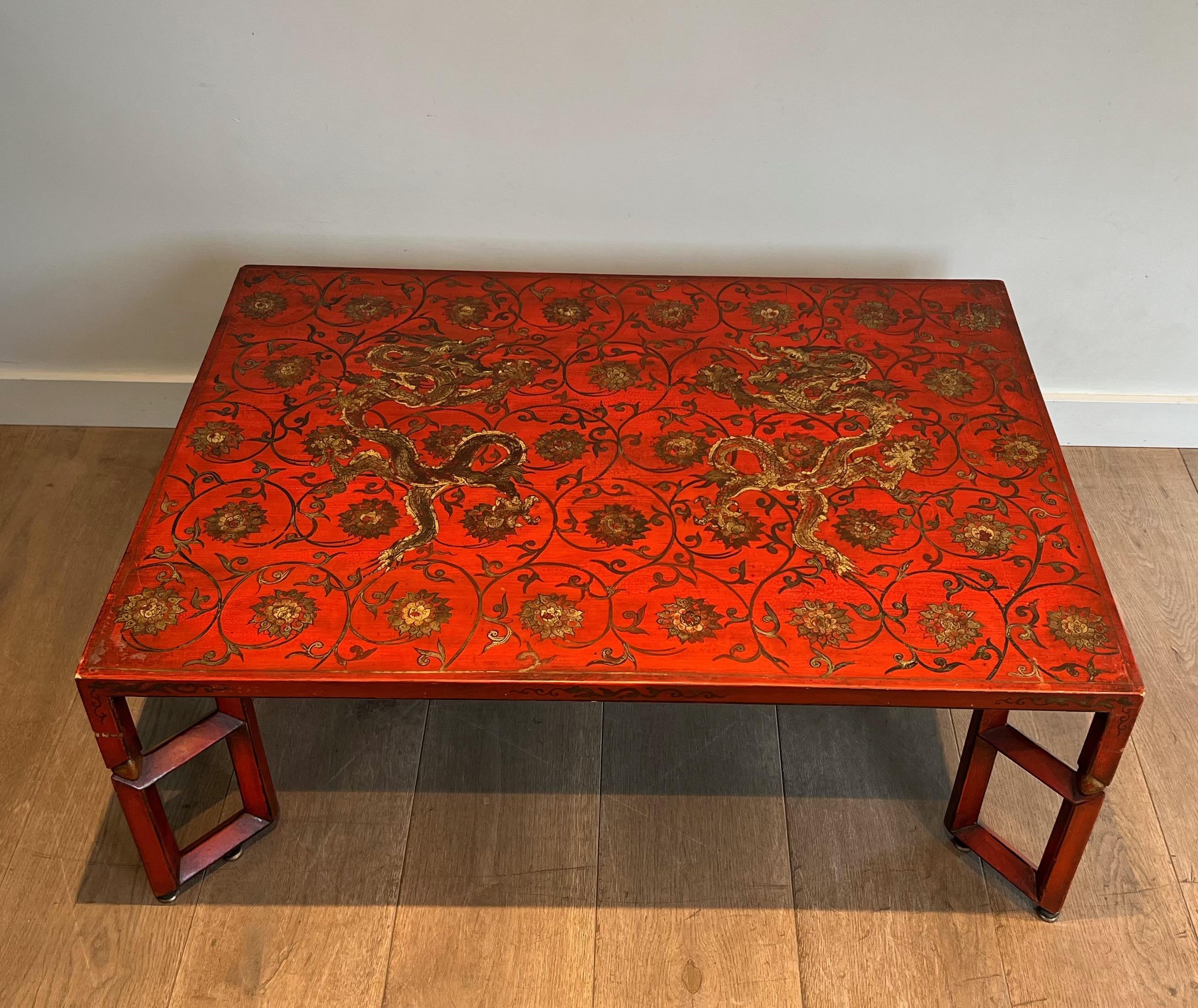 This large red lacquered coffee table is decorated with dragons, interlacing and floral motifs in polychrome and gold tones. This is a French work. Circa 1970.