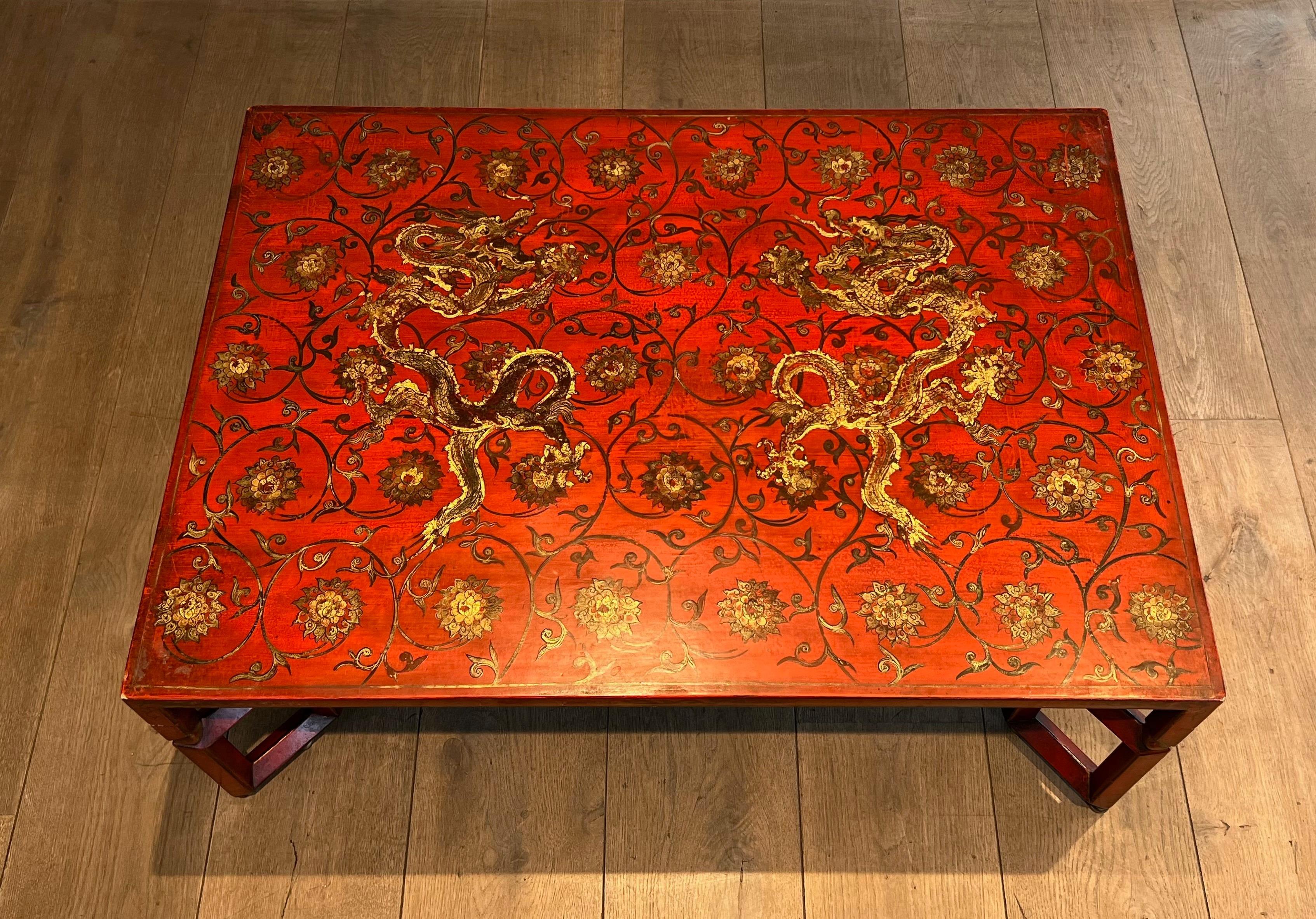This very nice large coffee table is made of red lacquered wood with gilt decors representing Chinese seenes.  This coffee table is decorated with dragons, interlacing and floral motifs in polychrome and gold tones. This is a French work. Circa 1970