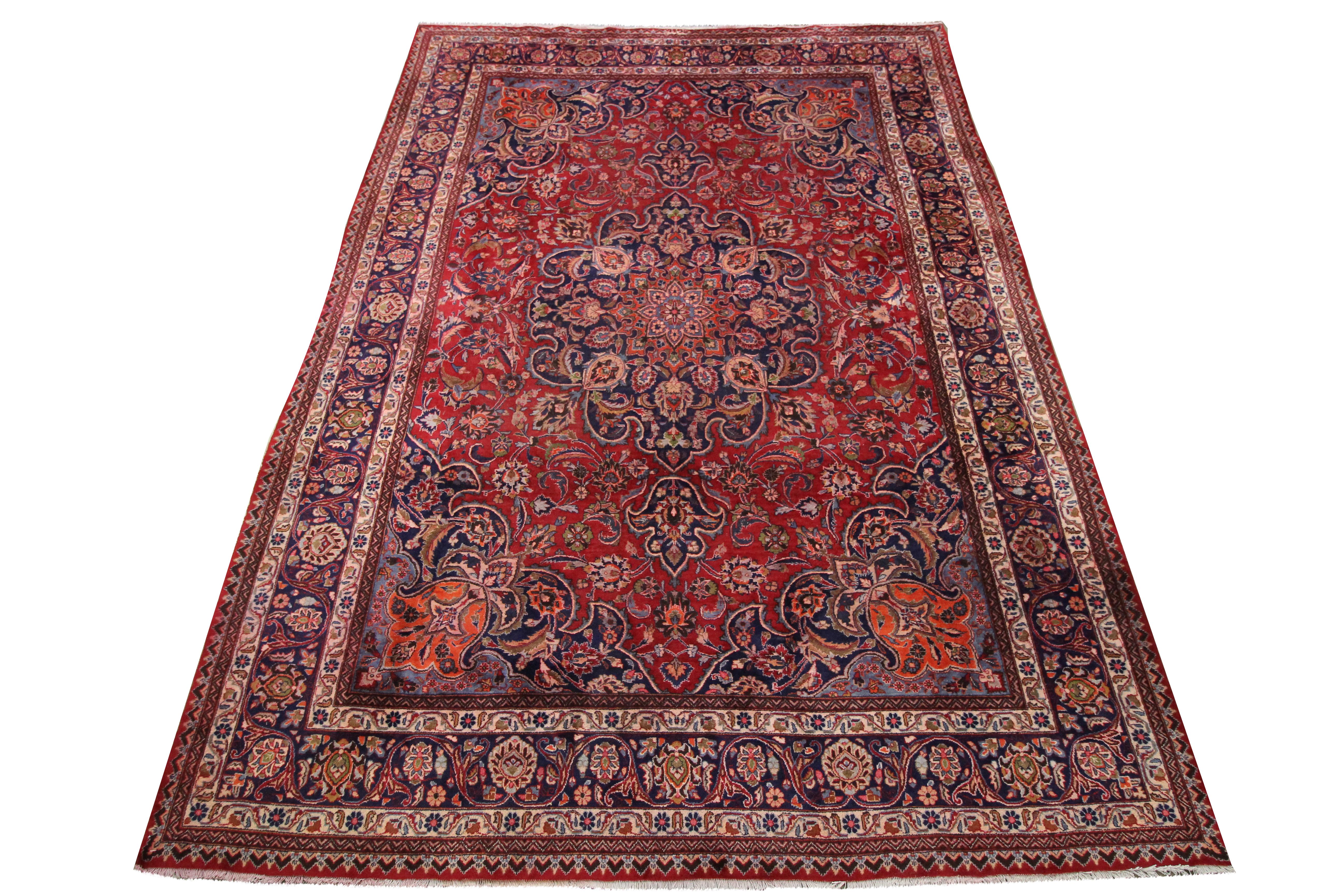 This vintage wool area rug is an excellent example of rugs woven by hand in the mid 20th century. Featuring a highly-decorative central medallion design that has been woven on a rich red background in blue, rust, cream and brown accents. This has