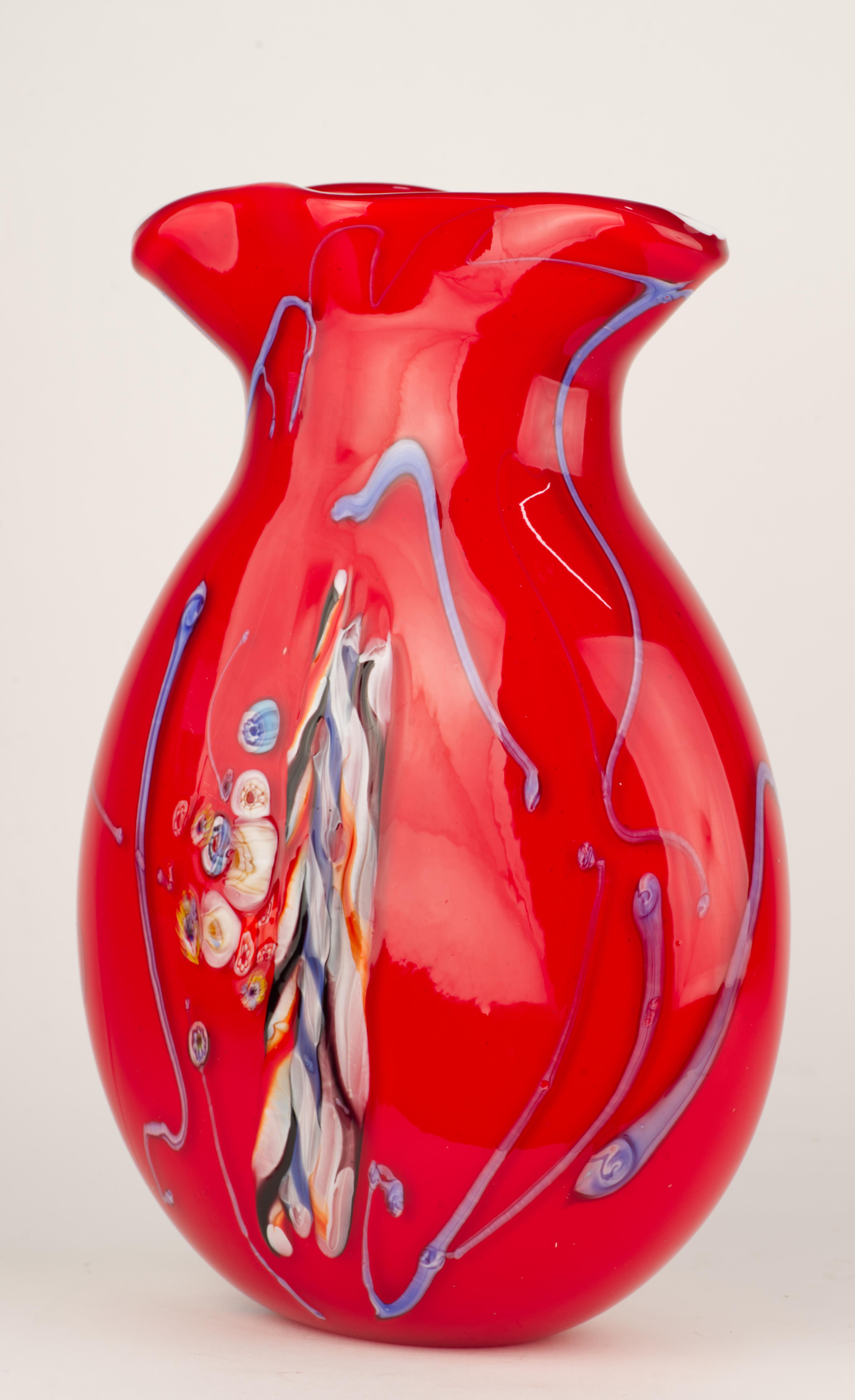  Il vaso in vetro di Murano vintage è stato realizzato a forma di fiasco con motivi grafici astratti su entrambi i lati del vaso. Il solido vetro rosso è stato decorato con inserti di millefiori e murine fuse multicolore, accentuati da motivi e
