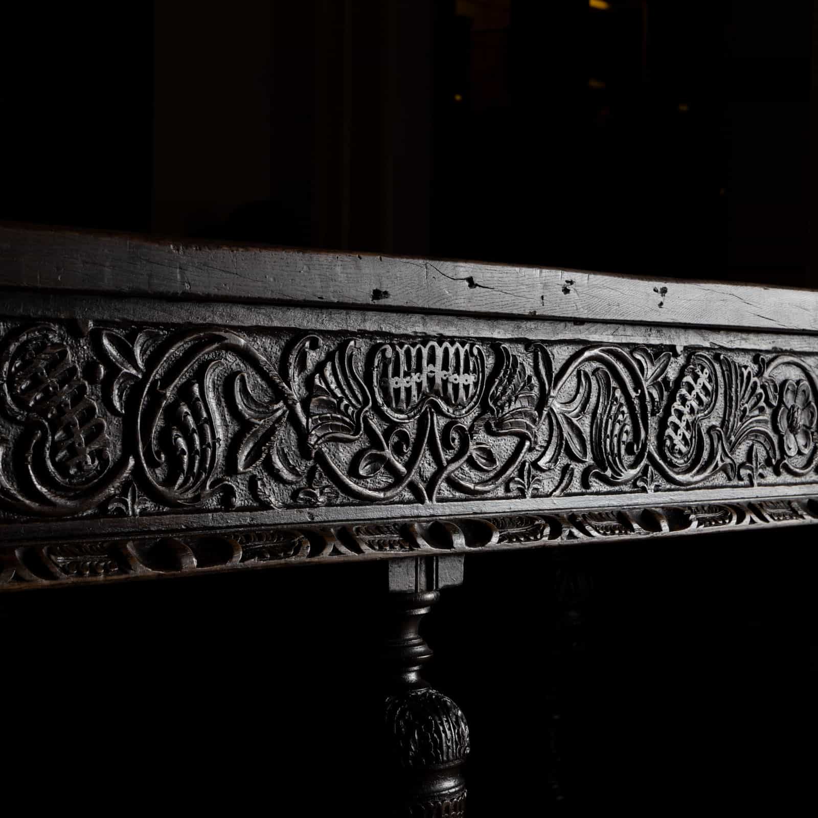 Very large dining table made of solid walnut with cup-and-cover baluster legs and carved relief with dragon ornament on the frame. The knee height is 61 cm. The legs are connected by intermediate struts. There are two knotholes on one long side. The