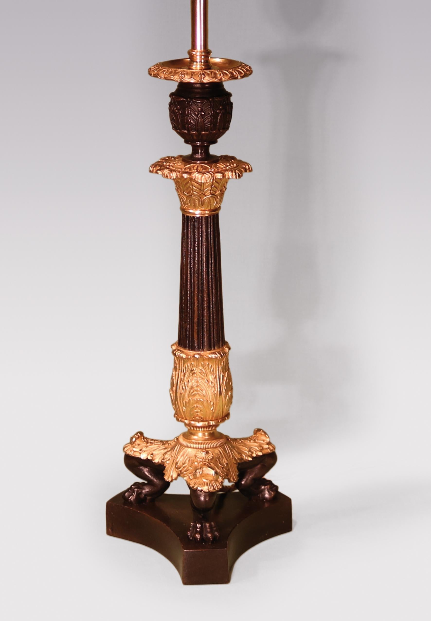A large early 19th century Regency period bronze and ormolu candlestick having acanthus nozzle above reeded tapering stem supported on acanthus and lions paw tripod legs ending on concave triform platform base. Now converted to electricity.