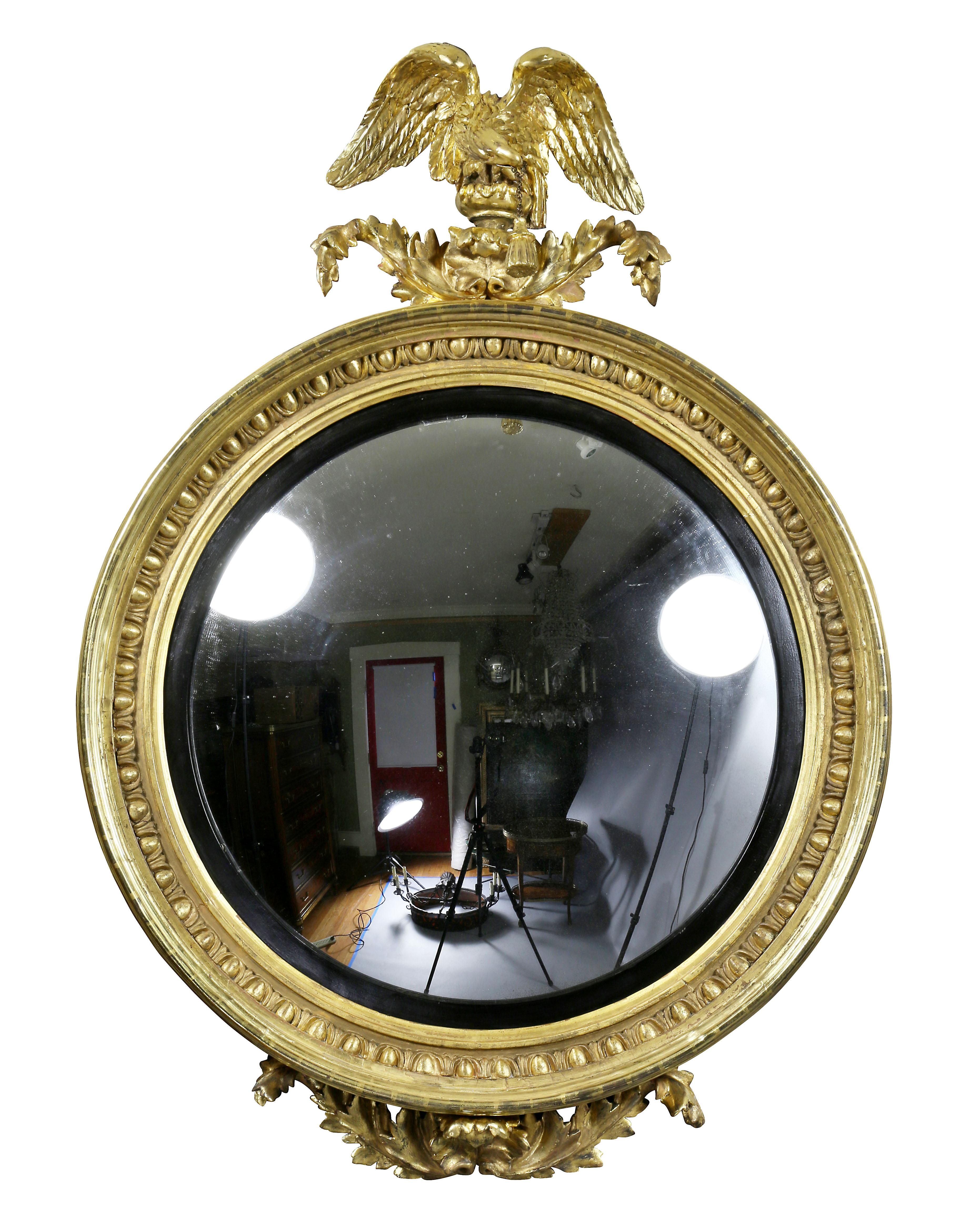 With eagle superstructure holding a tassel flanked by acanthus leaves over a circular convex mirror set in an egg and dart molded frame with ebonized inner ring. Base with acanthus spray