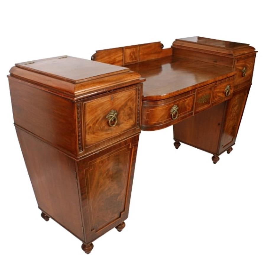 Early 19th century Regency mahogany pedestal sideboard raised on eight short turned feet.


The sideboard has a rosewood cross banding to the top edges with a boxwood line inlay.


The middle section has a long drawer disguised as three