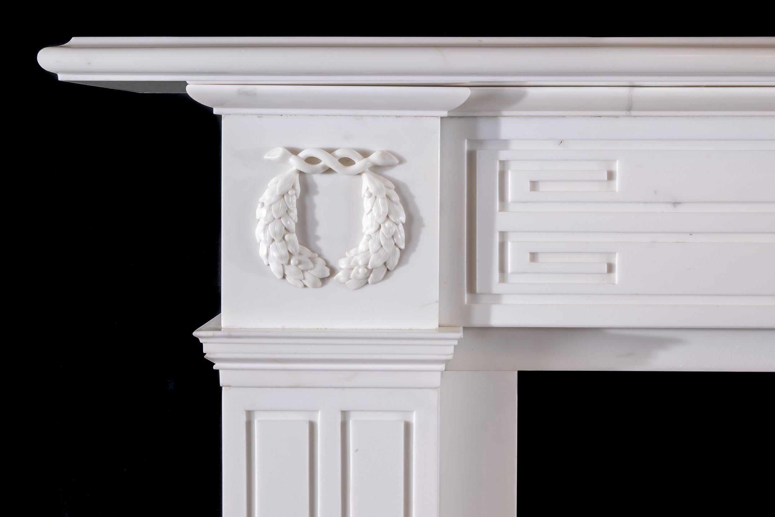 Imposante cheminée en marbre statuaire de style Régence, dont la frise et les jambages sont ornés de motifs géométriques audacieux, et dont les embouts sont ornés de couronnes de laurier. Ce design étonnamment moderne, intégré dans le style