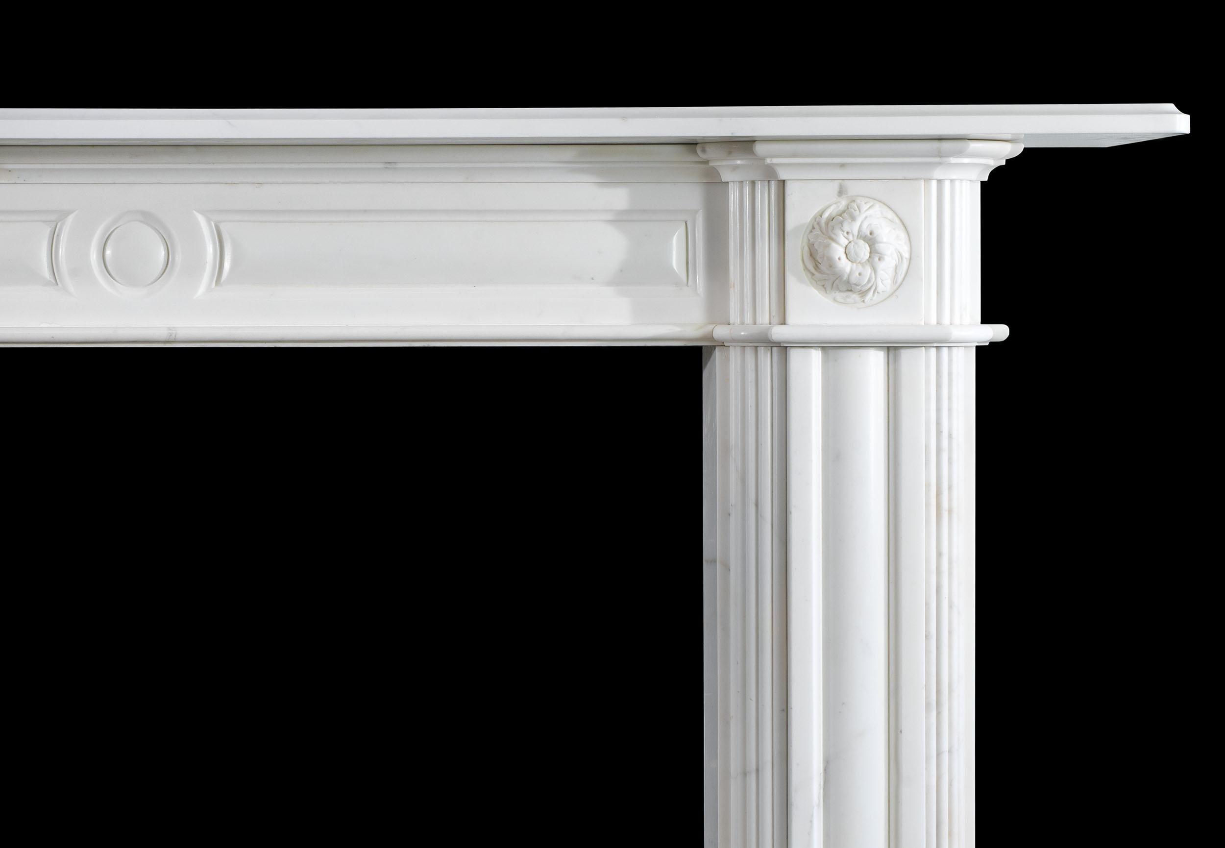 A large Regency white statuary marble Chimneypiece with reeded and moulded jambs and panelled frieze, which is flanked by a pair of carved foliate rosette corner blocks, beneath a simple moulded shelf.
English, Circa 1820.
