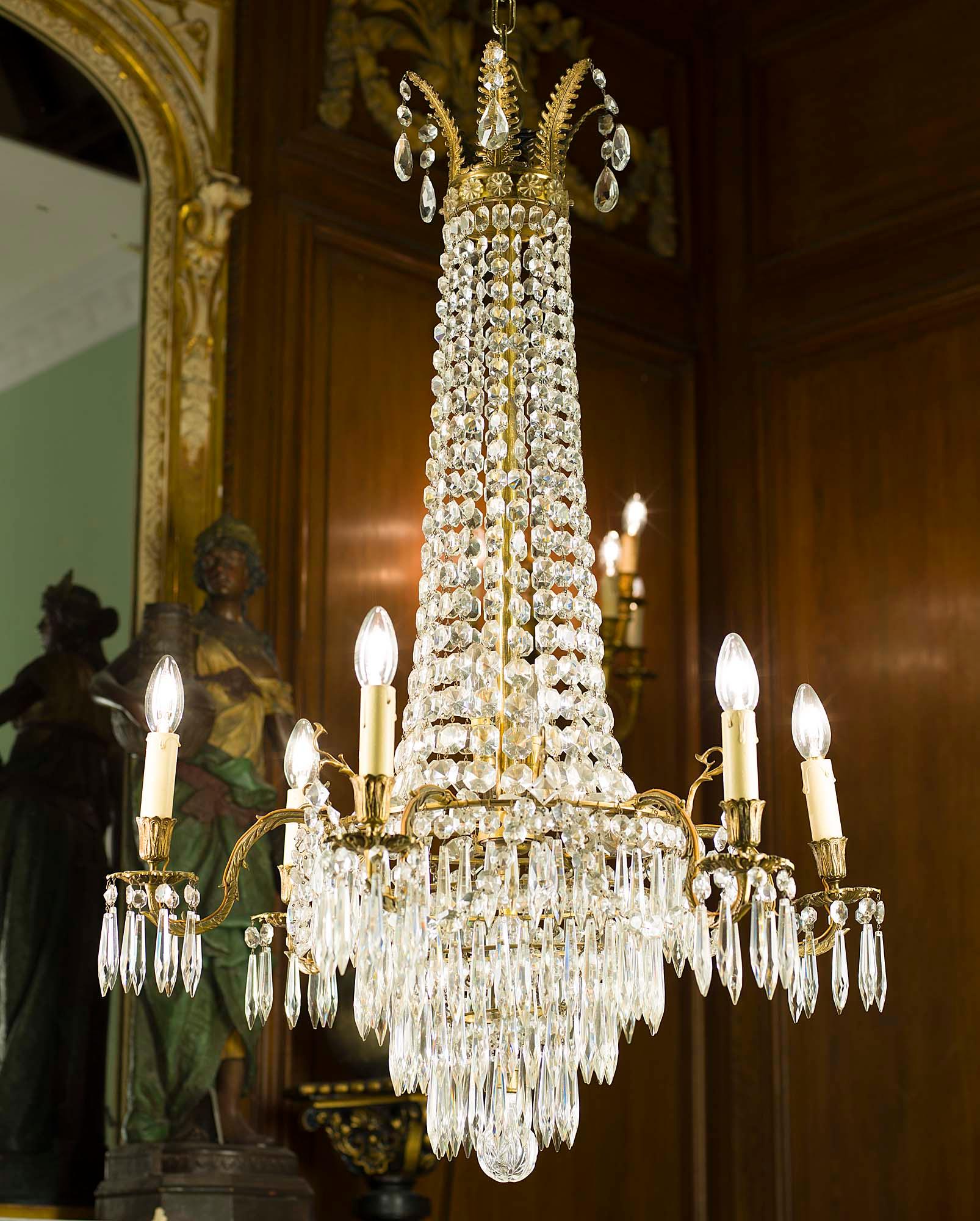 A large Regency style cut glass and gilt bronze six light antique chandelier, with tented beaded ropes descending from the corona to the waterfall of profusely hung spear drops weighted by a large cut glass globe.
English, early 20th century.