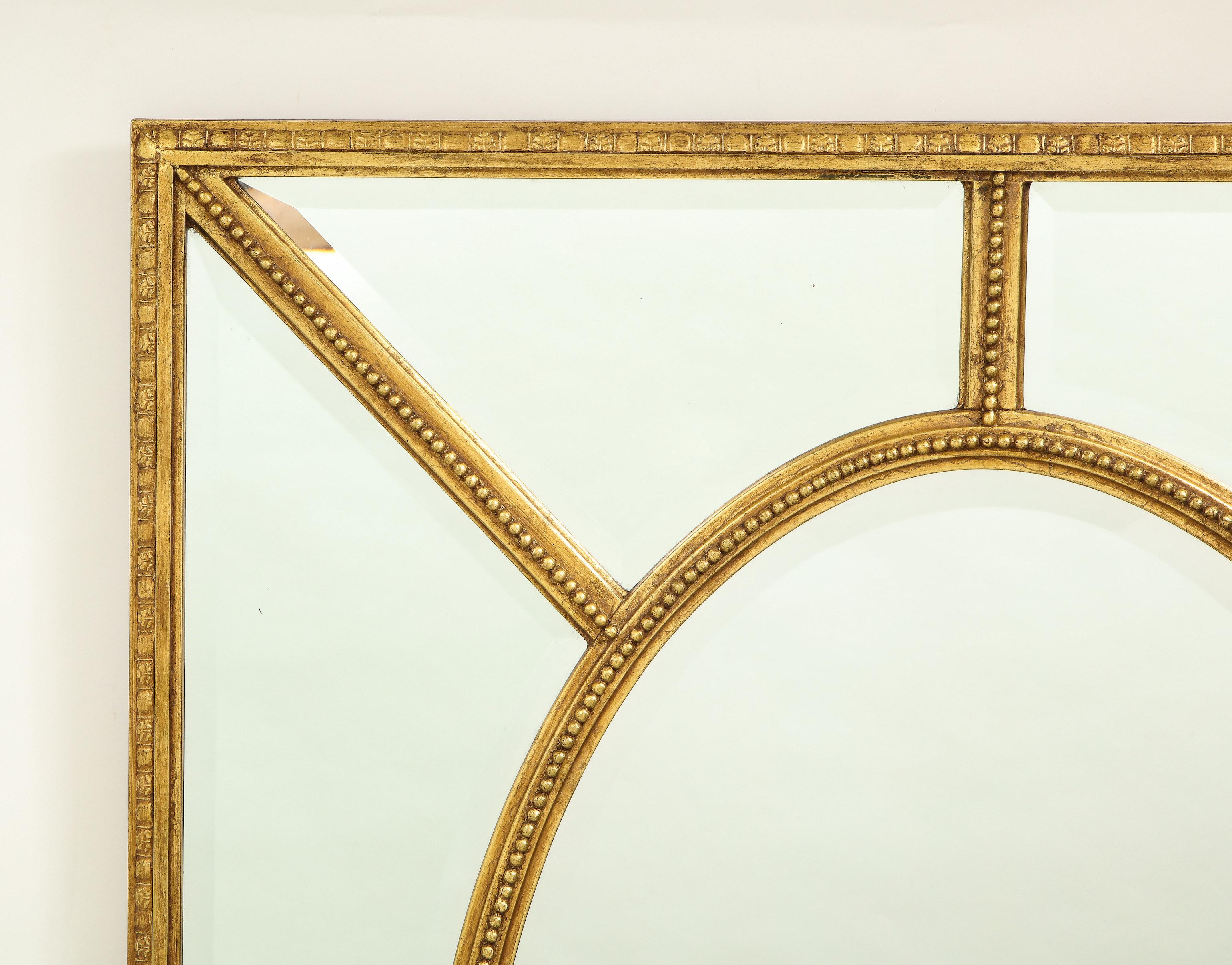 The rectangular mirror centered by an oval plate surrounded by border plates separated by a beaded and foliate-carved frame.