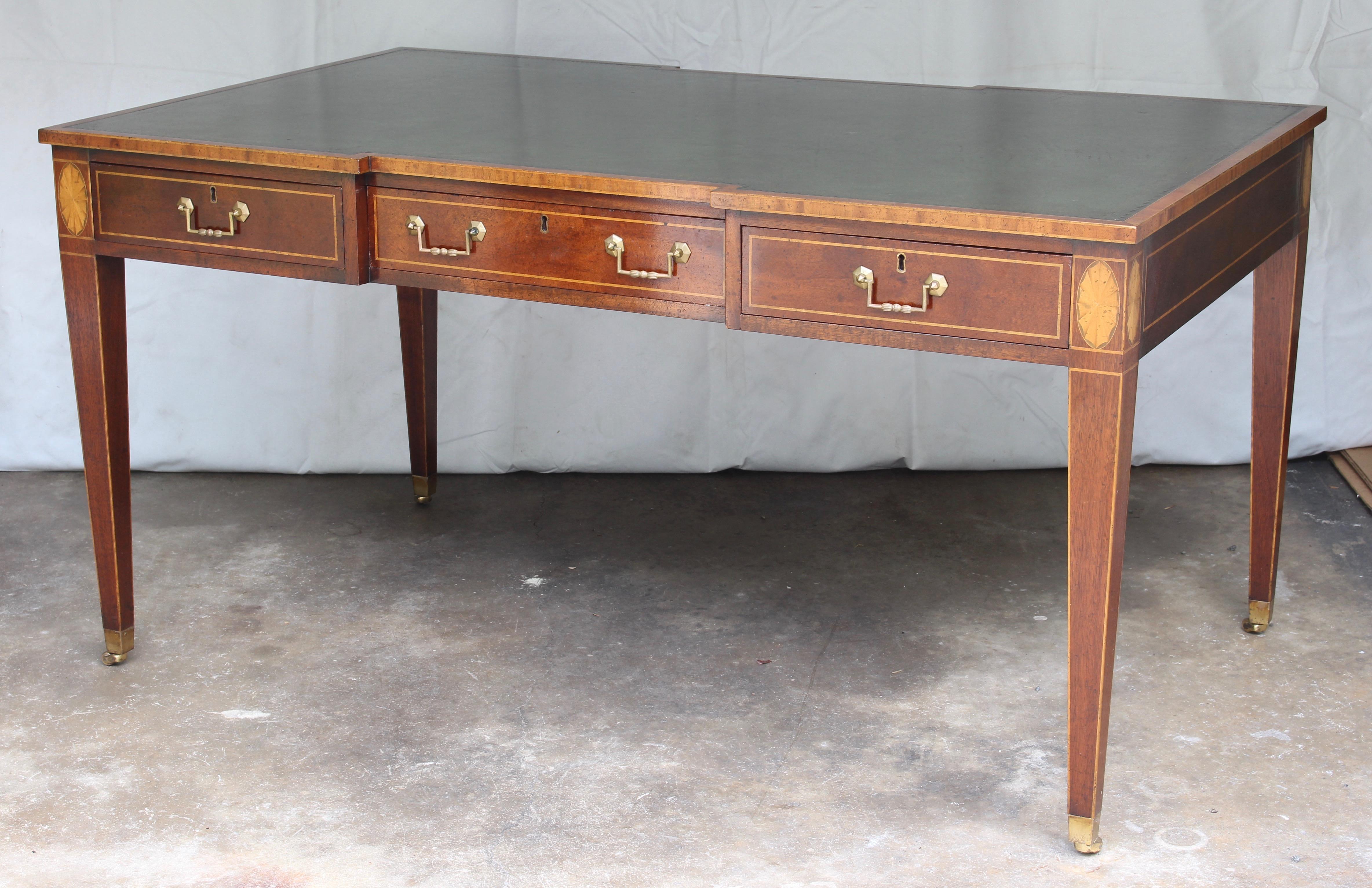 An exceptionally fine late 20th century mahogany Regency style leather topped writing table or desk by Holland & Co. with three drawers on both sides resting on square tapering legs terminating in brass casters.