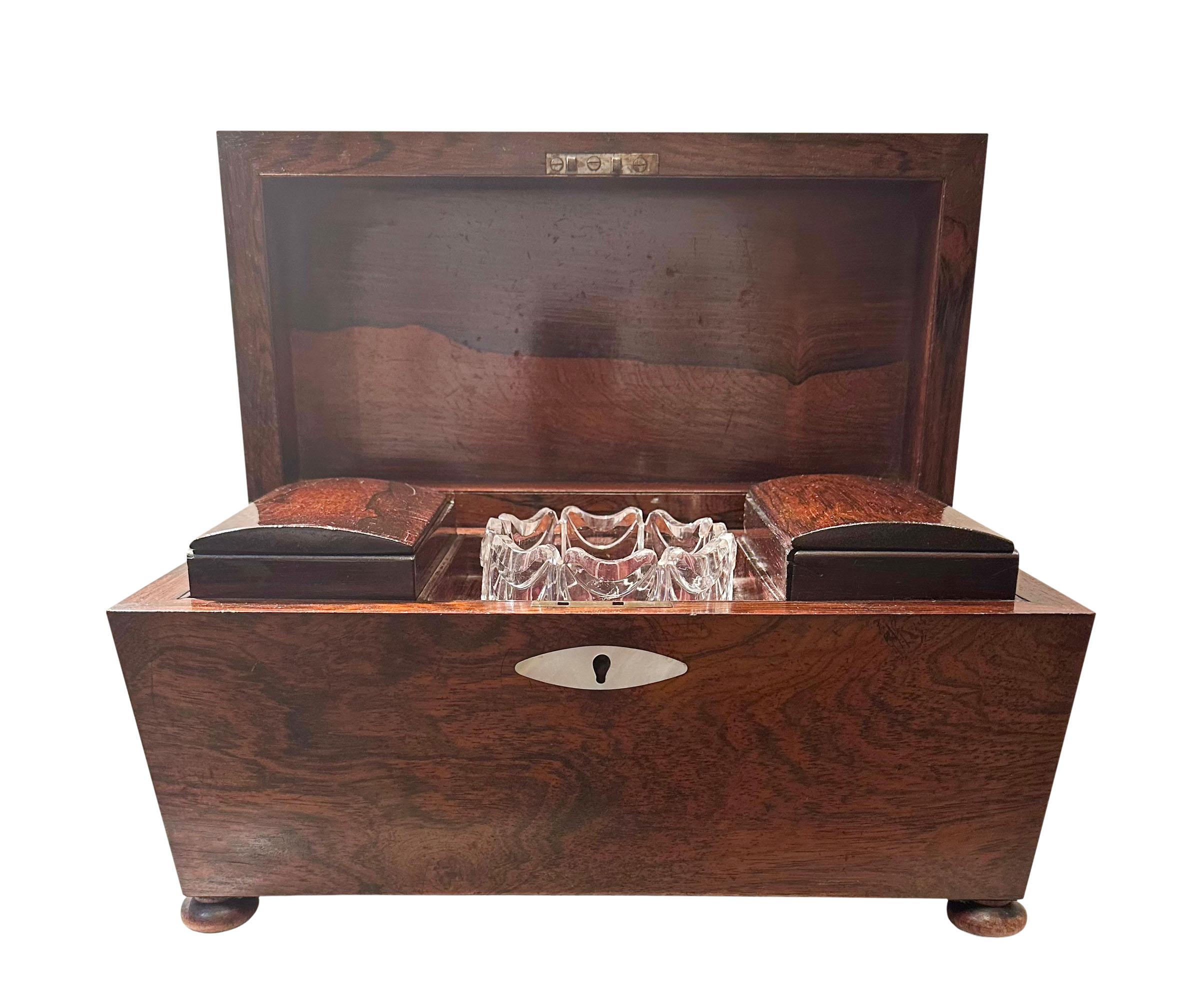 A large sarcophagus shaped rosewood tea caddy with a semi domed top. Original glass inside and two tea compartments. Mother of pearl inlaid escutcheon. On bun feet. The interior is five inches deep with each tea compartment four and a half inches.