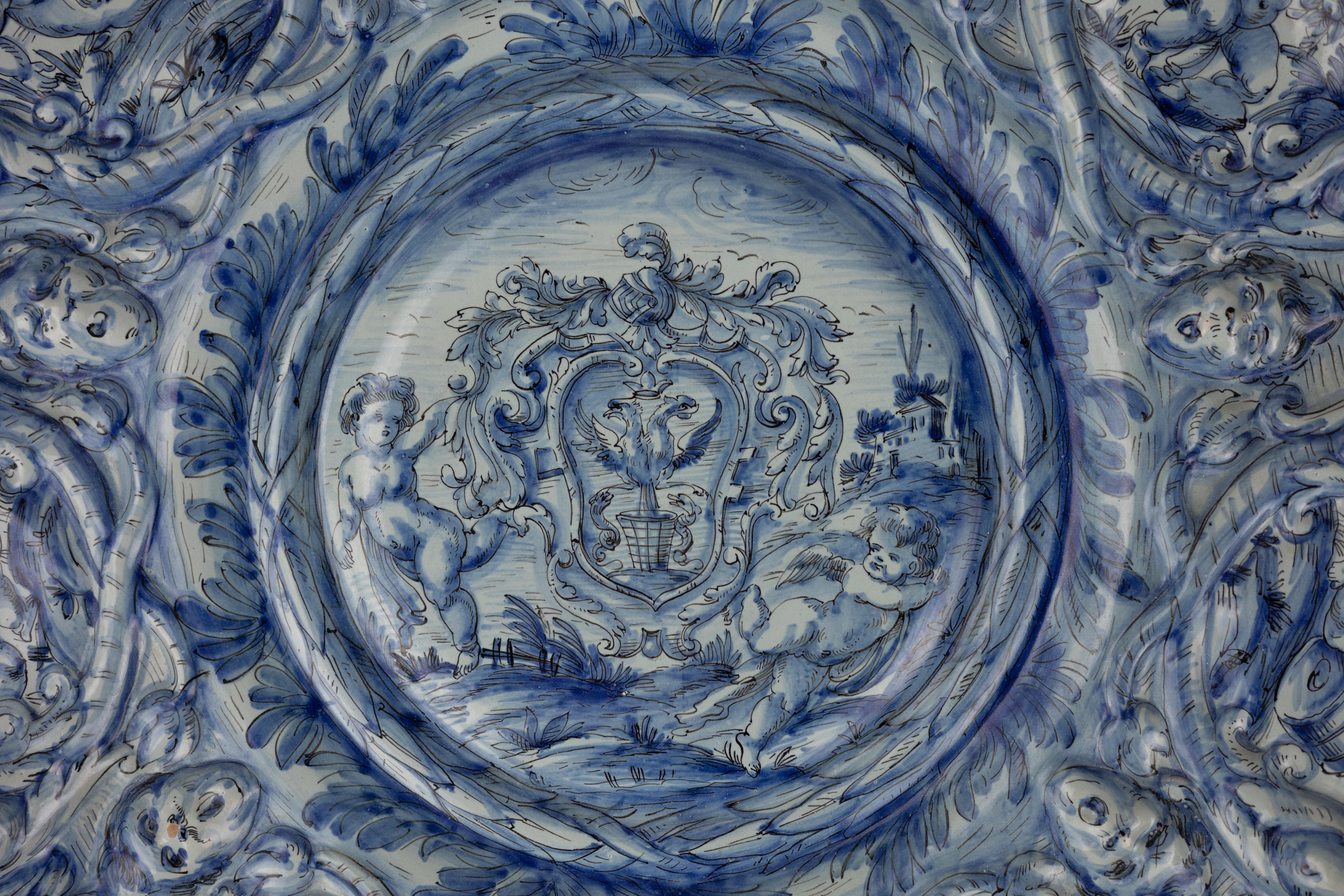 A monumental blue and white maiolica charger, made by Cantagalli, circa 1880. The charger is elaborately decorated with grotesques and putti molded in relief and a central armorial representing the Holy Roman Empire.

Ulisse Cantagalli was a