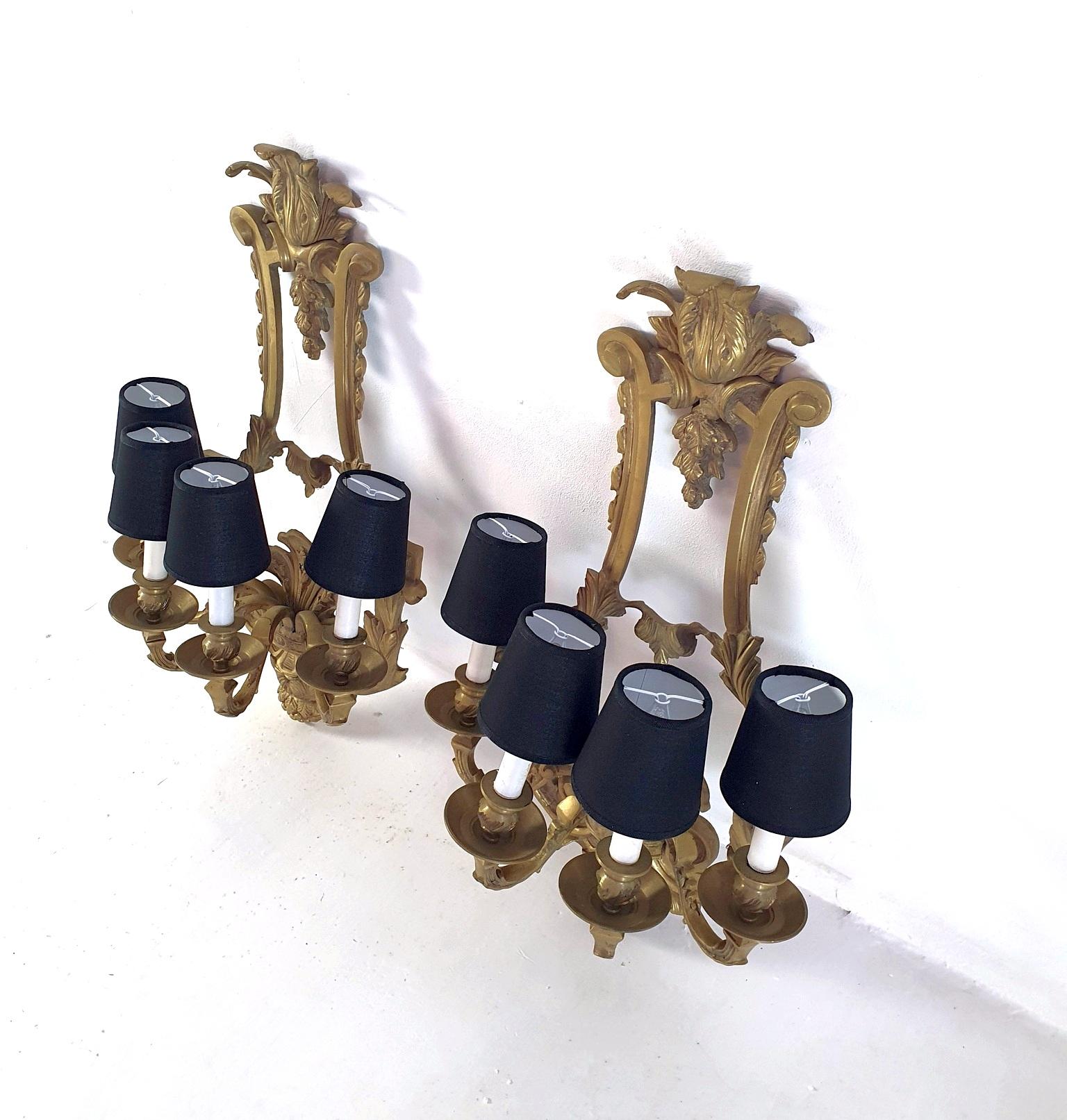 Monumental and unusual pair of finely decorated Renaissance wall sconces produced circa 1930-1940 made in cast bronze. Each sconce has four candleholders made for E14 lamps. Can be used with naked lightbulbs or with small chandelier shades. Each