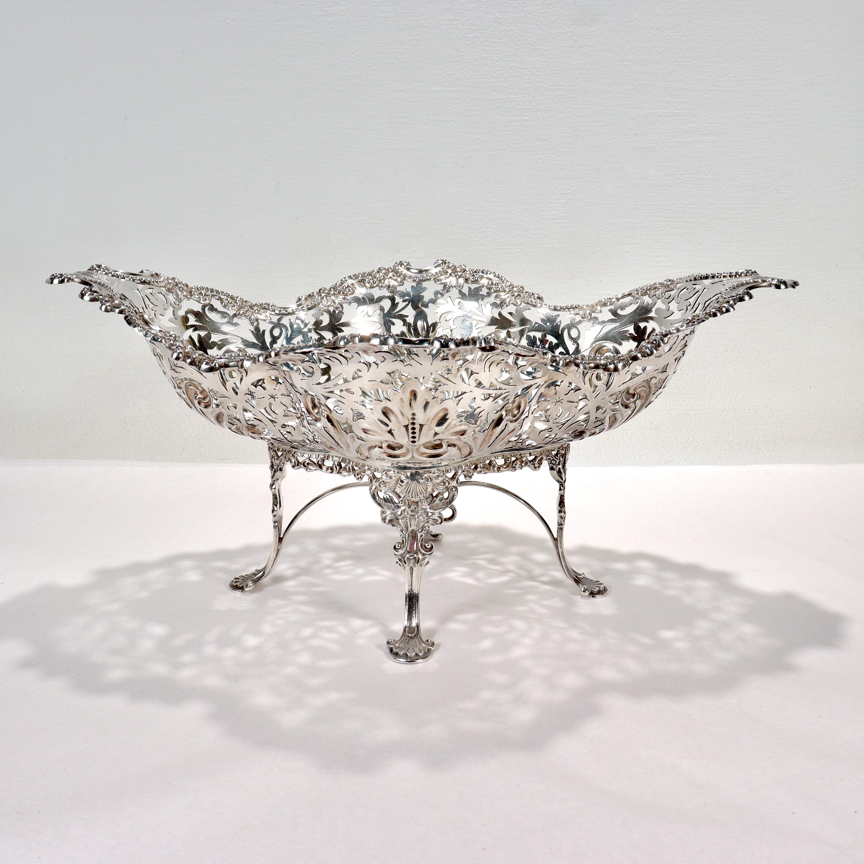 A fine large Georgian style reticulated footed basket.

In sterling silver.

By James Dixon & Sons of Birmingham, England.

The pierced bowl has a shaped rim and heart shaped devices in its interior and is supported by an ornate stand on cabriole