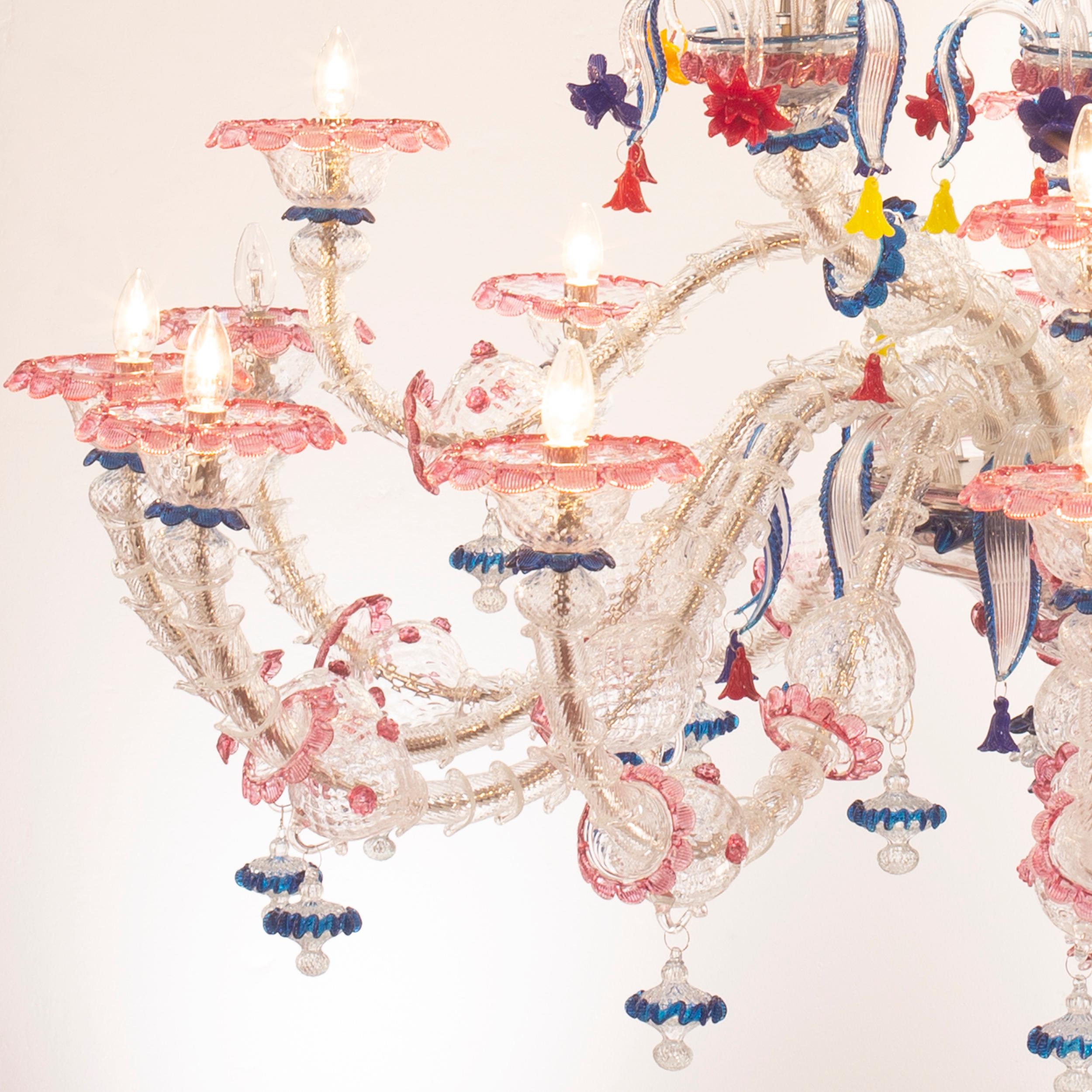 Kia Ora Kronleuchter mit 24 Lichtern aus klarem Murano-Glas mit blauen und rubinroten Verzierungen und mehrfarbigen Details aus Glaspaste.

Kia Ora ist die Kombination der traditionellen venezianischen Struktur mit knalligen Farben. Die