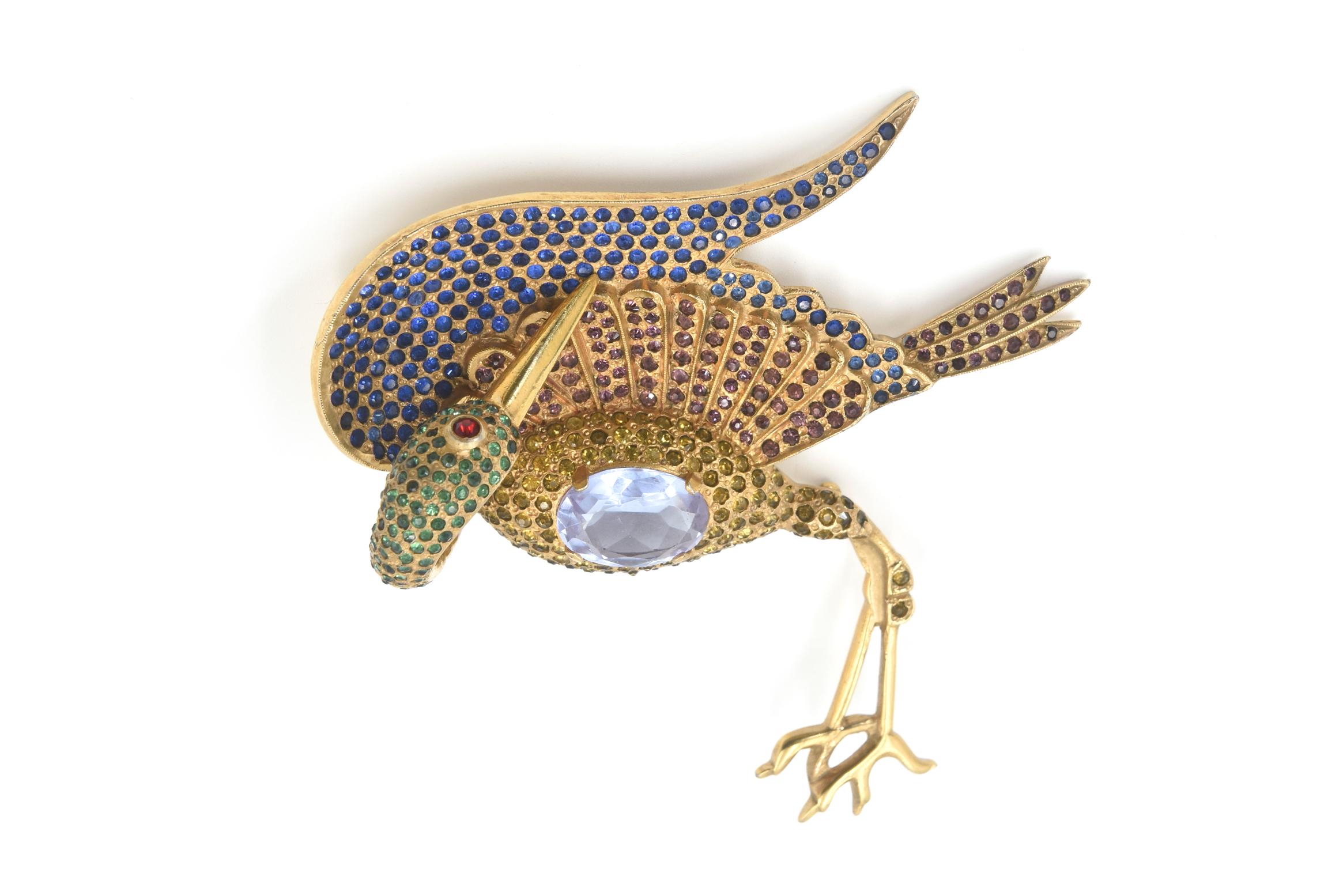 Extraordinaire broche en forme de grue, rehaussée de petits strass bleus, verts, bruns et dorés, ainsi que d'un grand cristal violet pour son ventre.  L'épingle est grande  3.75