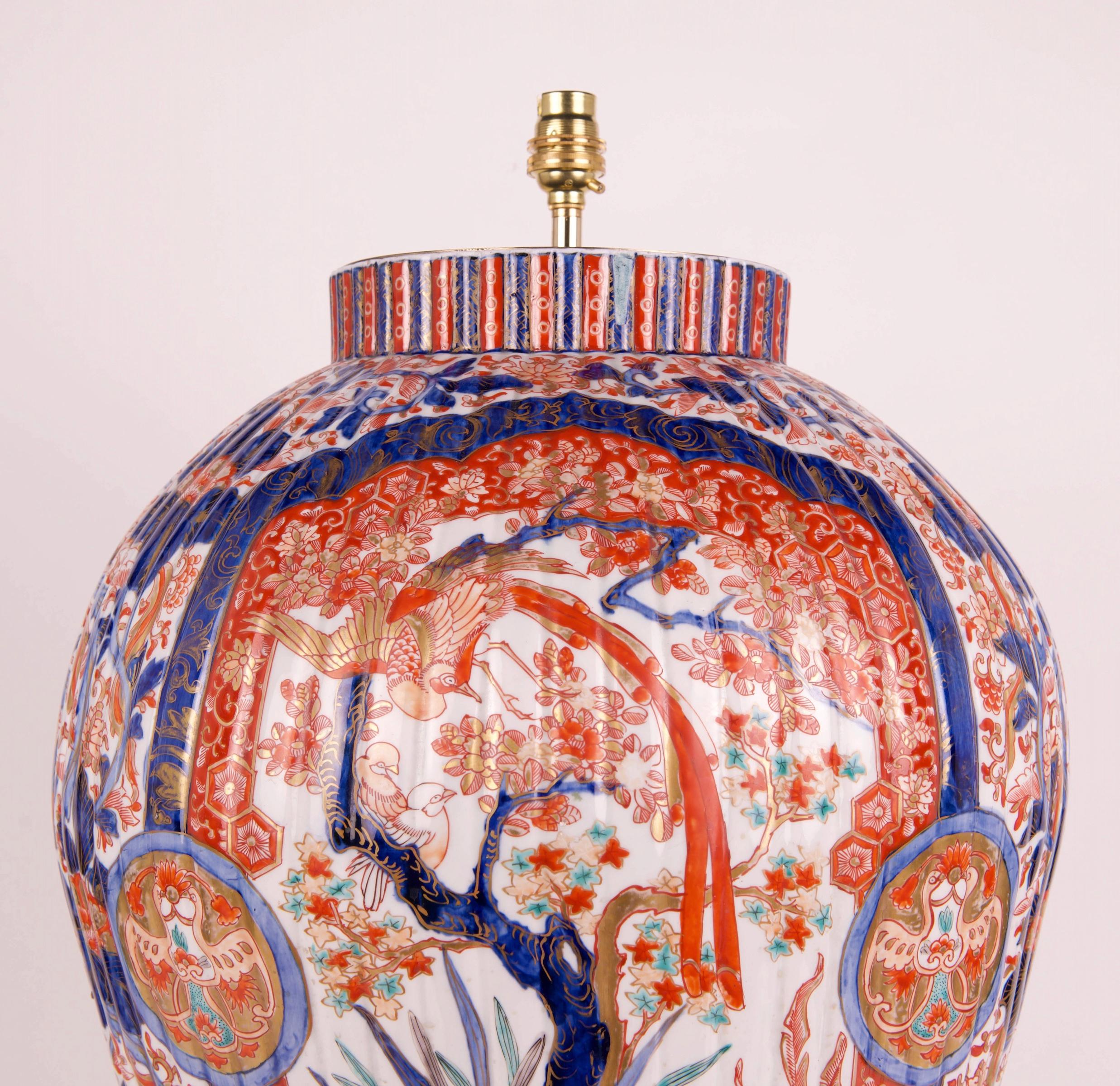 A wonderful very large 19th century Japanese Imari vase, with ribbed body form, decorated throughout in the typical Imari palette of iron reds and blues with gilded highlights on a white background, with two large panels depicting wonderful garden