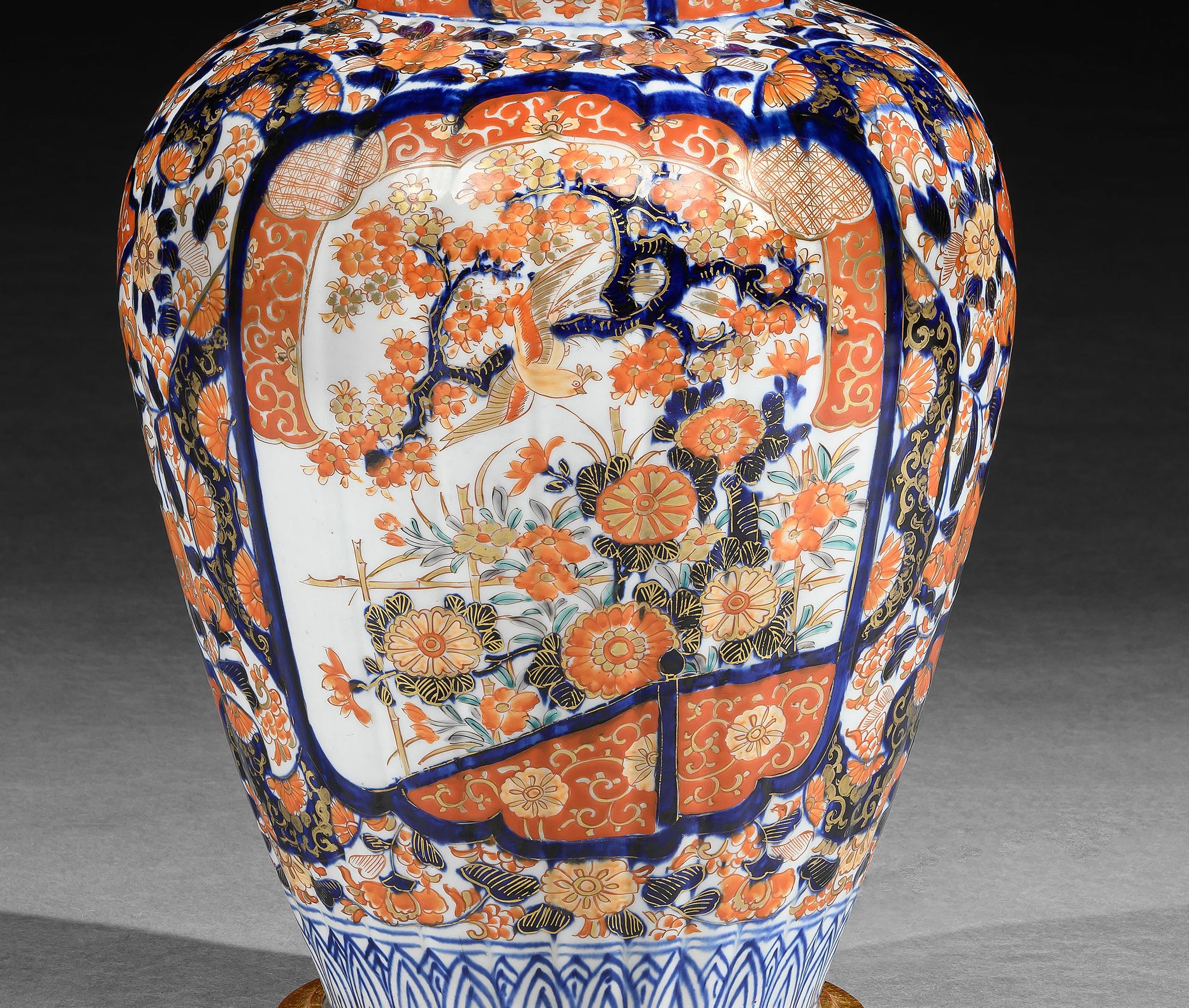 Un superbo vaso Imari giapponese del XIX secolo, con corpo a coste, decorato nella tipica tavolozza Imari di rossi e blu ferrosi con riflessi dorati su sfondo bianco, con due grandi pannelli raffiguranti meravigliose scene di giardino con alberi in