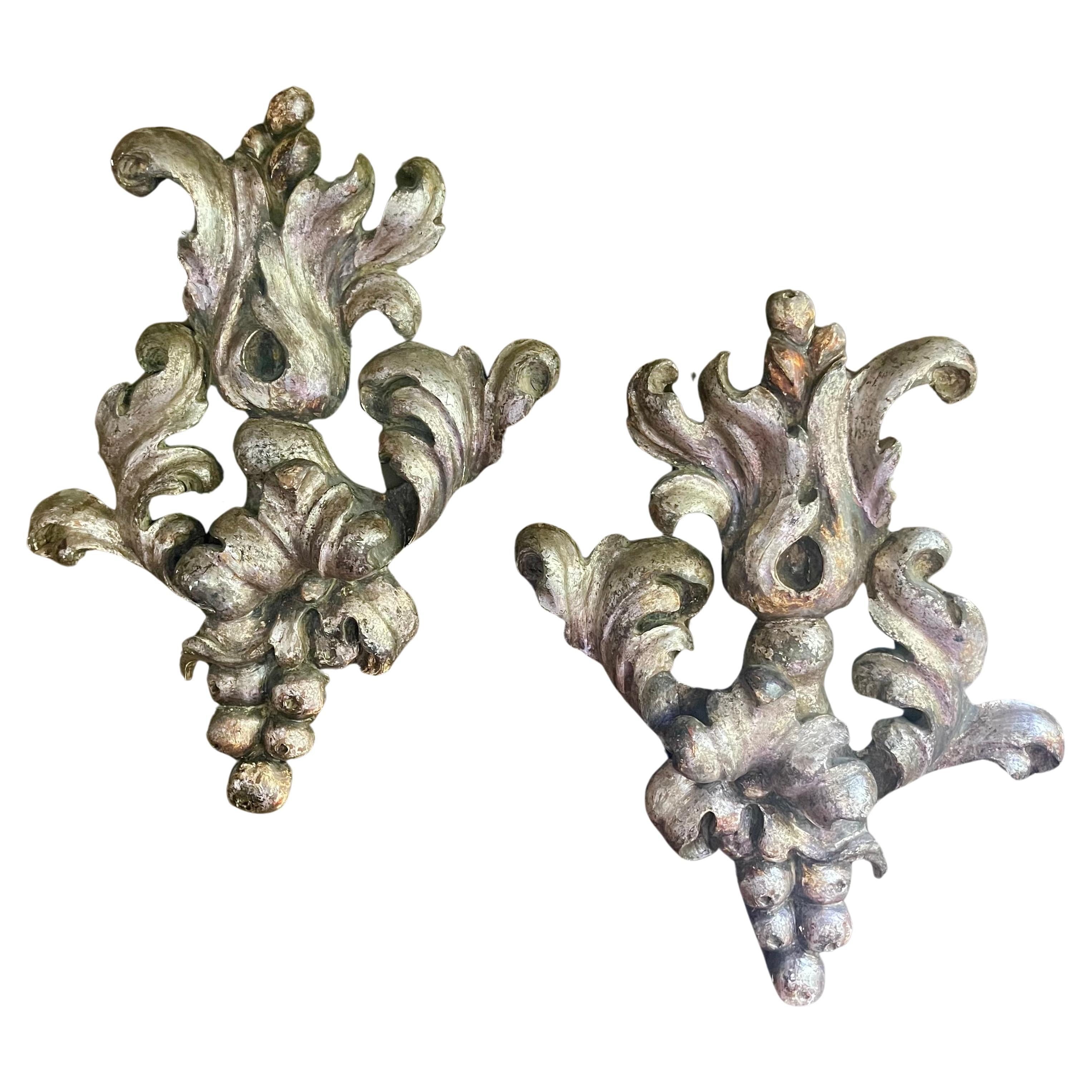 Set or pair of robustly carved silver Giltwood wall trophies or wall appliqués .In the baroque style with dramatic acanthus scrolls and flourishes .Of wood with iron hangers on back.

Baroque carving often had multiple ideal viewing angles, and