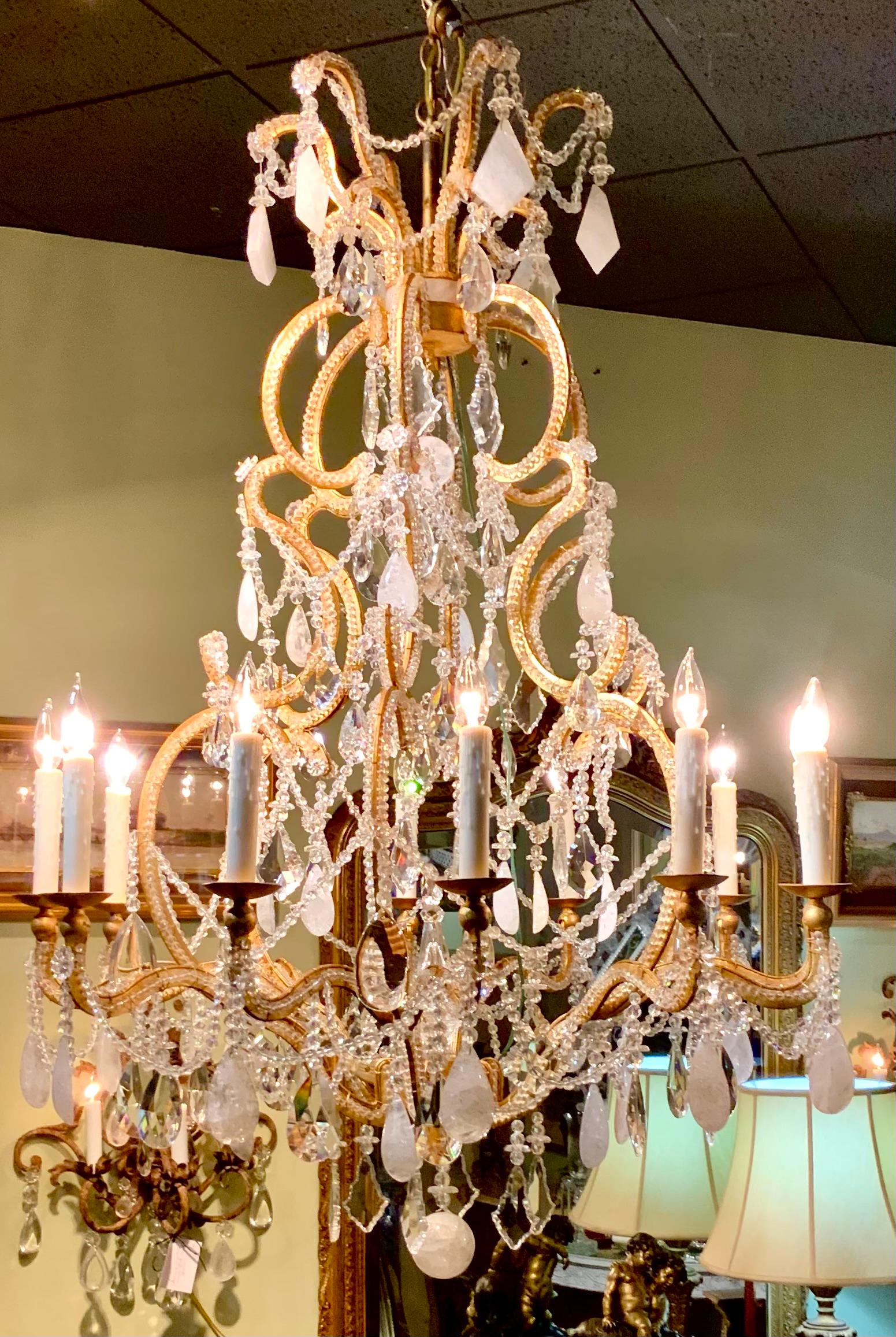 Large in scale this chandelier exhibits special features consisting 
Of bead work and a large amount of rock crystal mixed with
Brilliant clear crystal. Scrolling wide spread arms exhibit an open
Cage effect. It has twelve arms that brightly