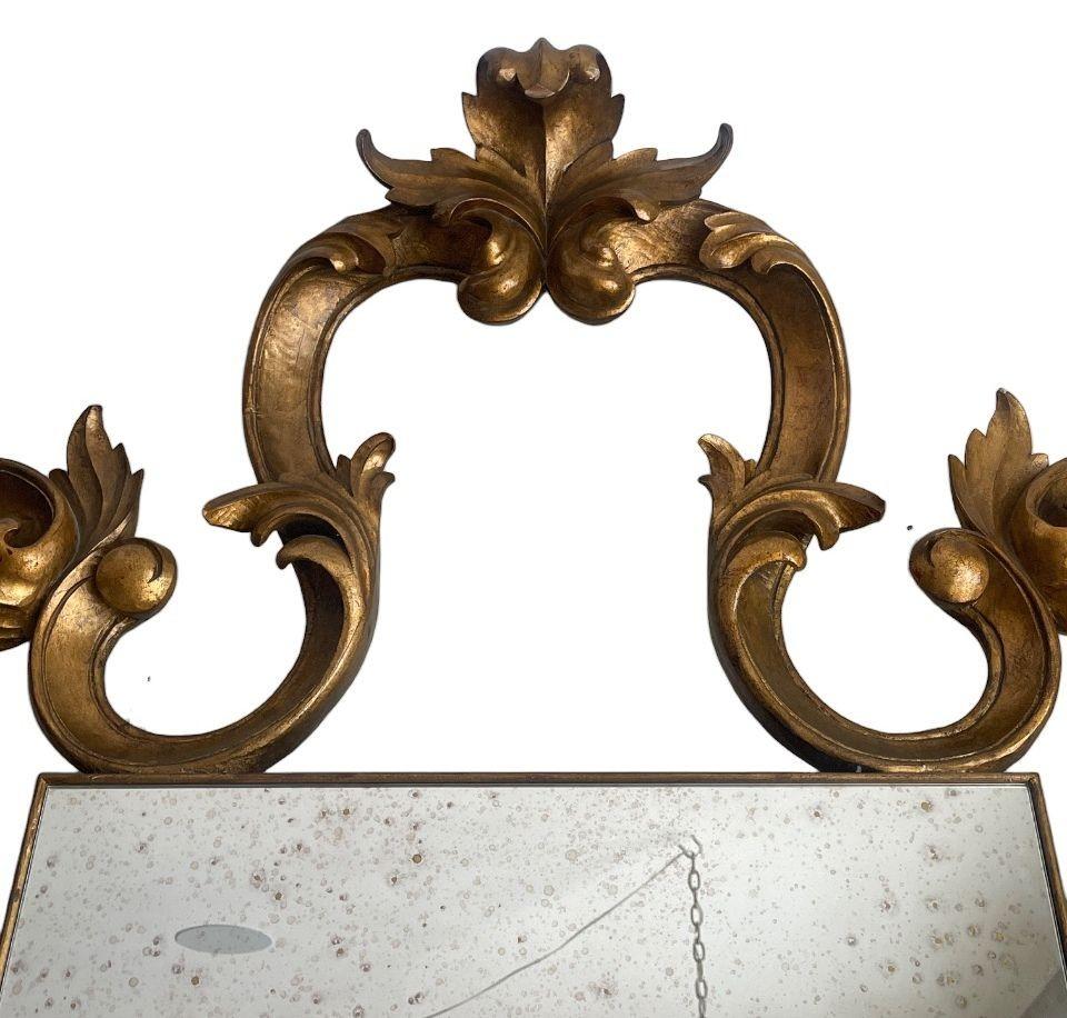 Uno specchio di grandi dimensioni in stile rococò con una cornice ornata e pannelli a specchio splendidamente anticati. La cornice scolpita in oro mostra foglie d'acanto che scorrono, motivi di conchiglie e curve asimmetriche caratteristiche dello
