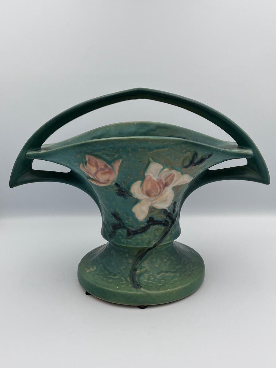Grand vase panier en céramique vert Magnolia de Roseville - 1943

Ce superbe vase à panier Roseville Magnolia est un bel exemple de poterie d'art américaine du milieu du XXe siècle, reprenant le motif emblématique Magnolia introduit par Roseville
