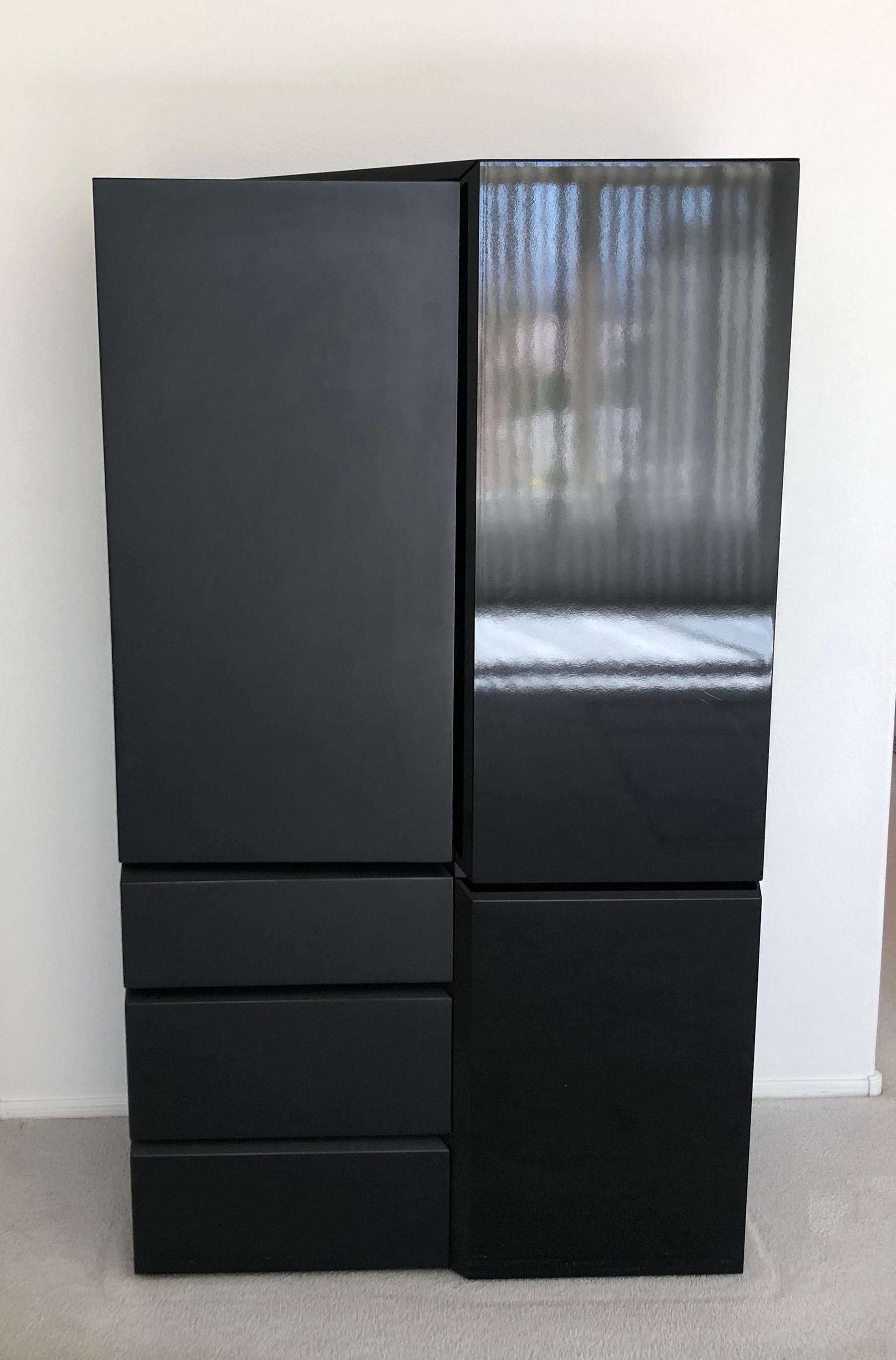 A large sculptural highboy cabinet by Rougier. This stunning cabinet features a tone on tone matte black and glossy black lacquer design. Piece is signed.