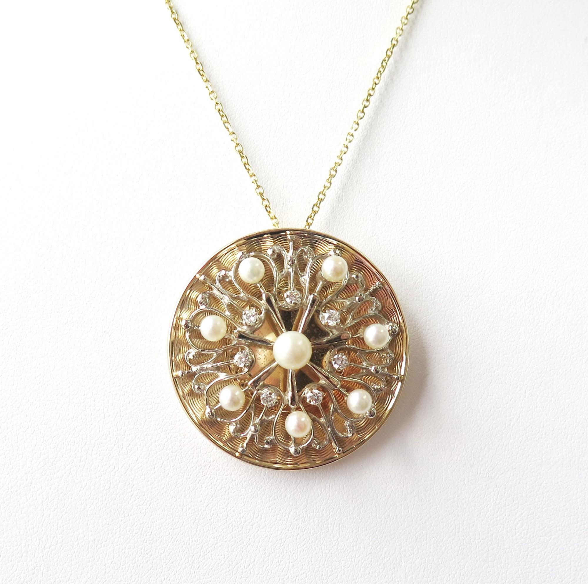 This large round statement pendant has a textured yellow gold background and a raised design of white gold swirls. There are 7 creamy white pearls in a circle and 1 center pearl.  A circle of 7 sparkly diamonds separates the center pearl.

14 karat