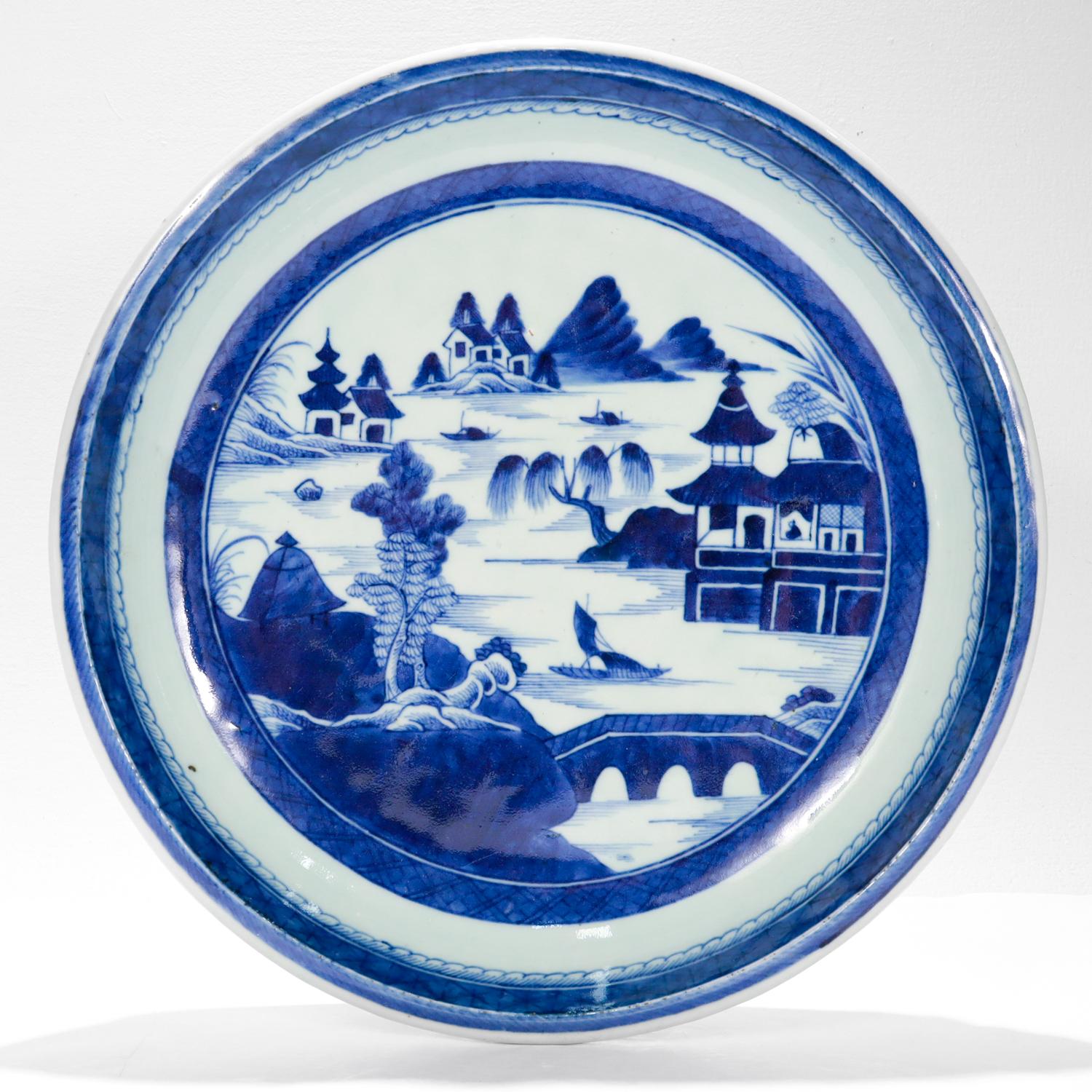 A fine antique Chinese export porcelain serving bowl or tray.

In the Canton pattern.

Decorated in underglaze blue depicting a mountainous Chinese village. The background has houses, a mountains, and a pagoda. The midground is a river with boats