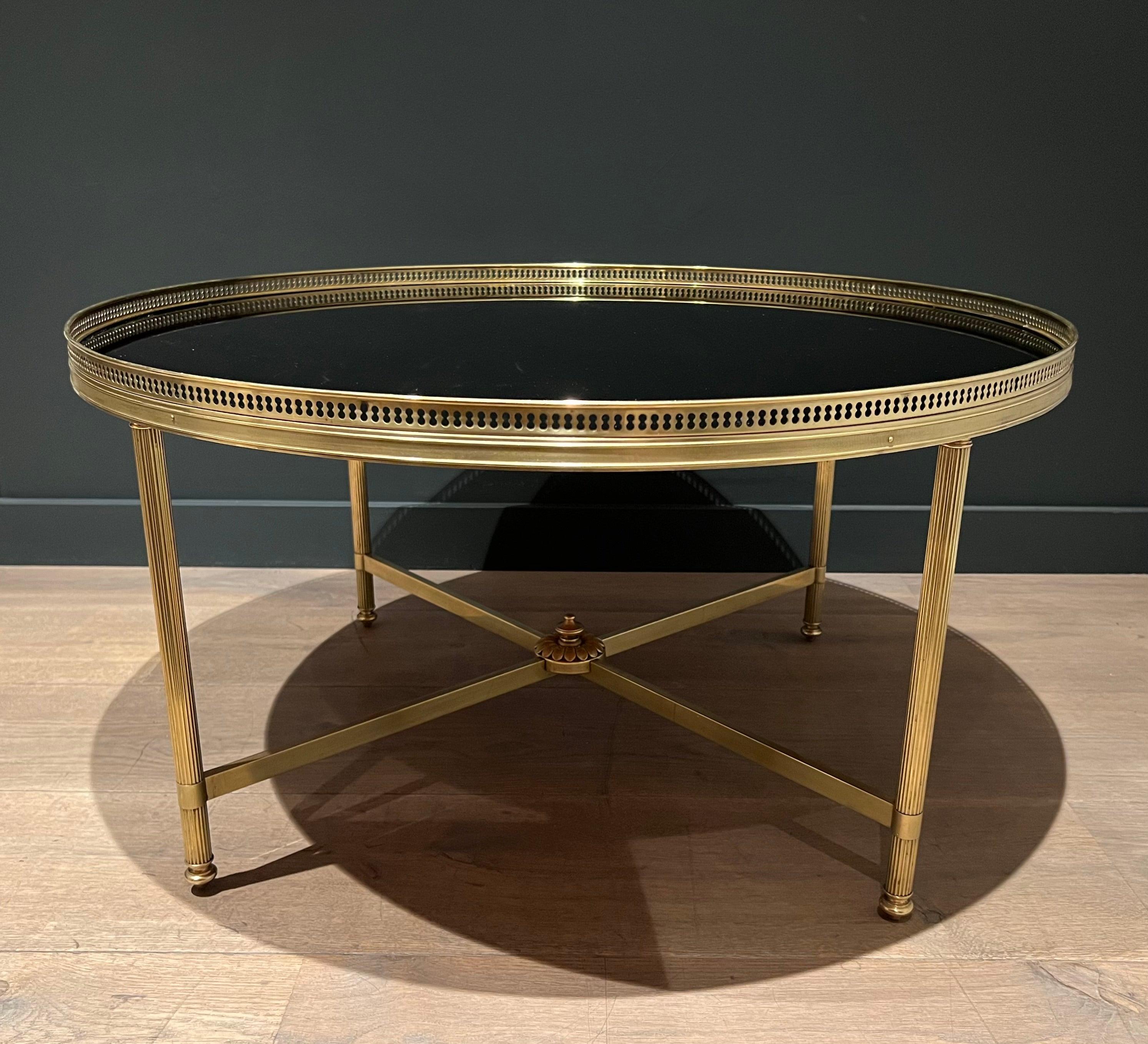 Cette grande table basse ronde est fabriquée en laiton avec un plateau en verre laqué noir. Ce modèle est particulièrement rare dans cette taille. Il s'agit d'un ouvrage français de la Maison Jansen. Circa 1940