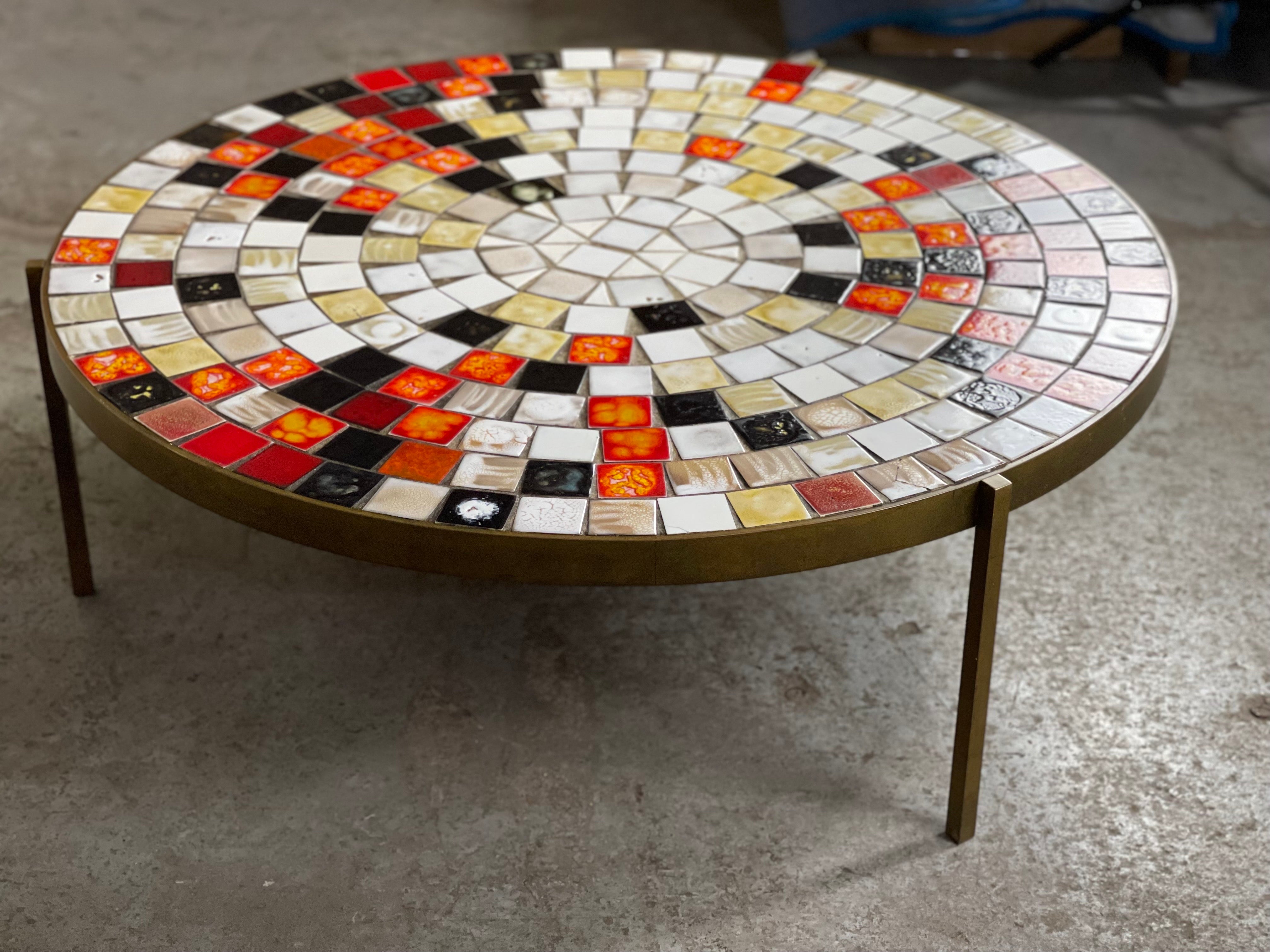 A fantastic classic mid-century cocktail table in a circular form with a heavy bronze frame and a ceramic tiled top in excellent colors. By Mosaic House. American, circa 1950s. It was in the same family - passed through generations - to you.