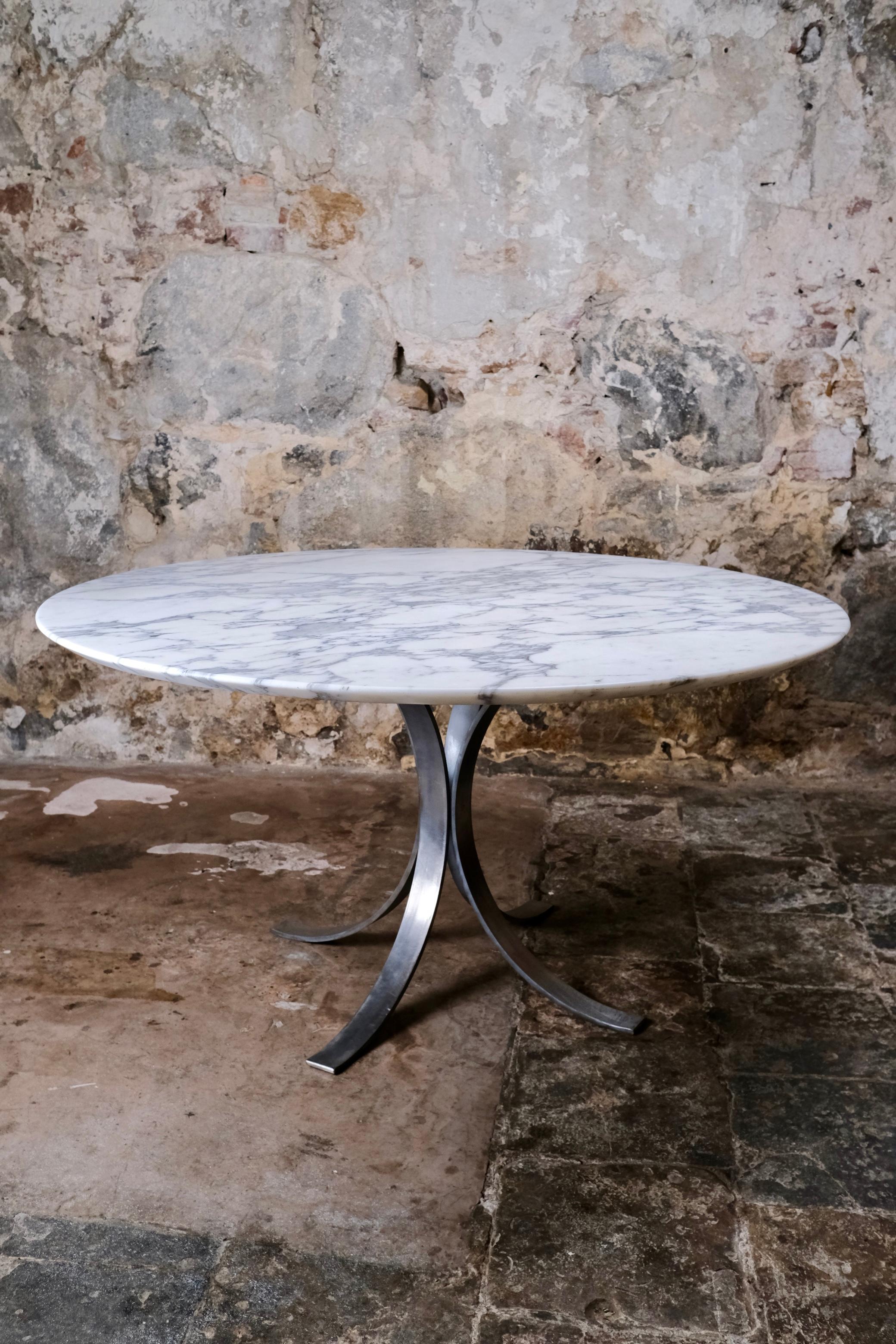 Una llamativa mesa de comedor redonda fabricada en Italia en la década de 1970, evocadora de la refinada estética asociada a Osvaldo Borsani. El grueso tablero es de mármol blanco de Carrara ricamente veteado, conocido por su elegancia intemporal y