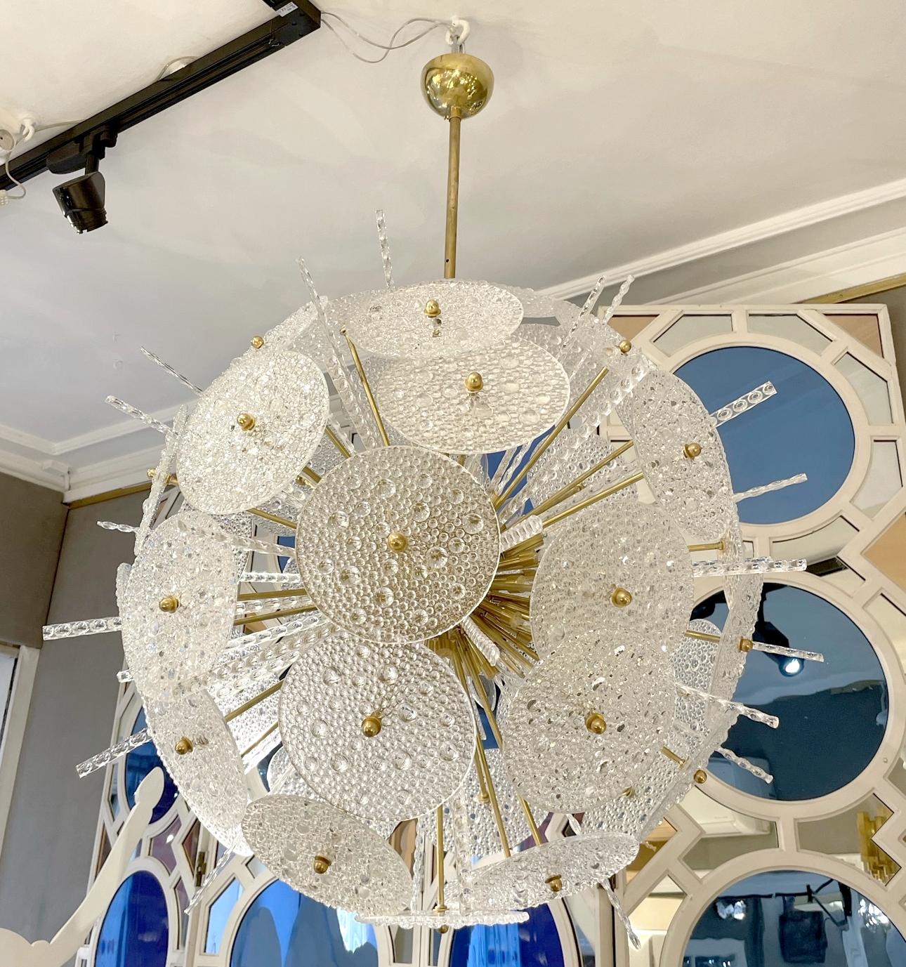 Murano glass and brass chandelier.
A structure made up of a sphere and brass rods supports frosted glass disks decorated with small 