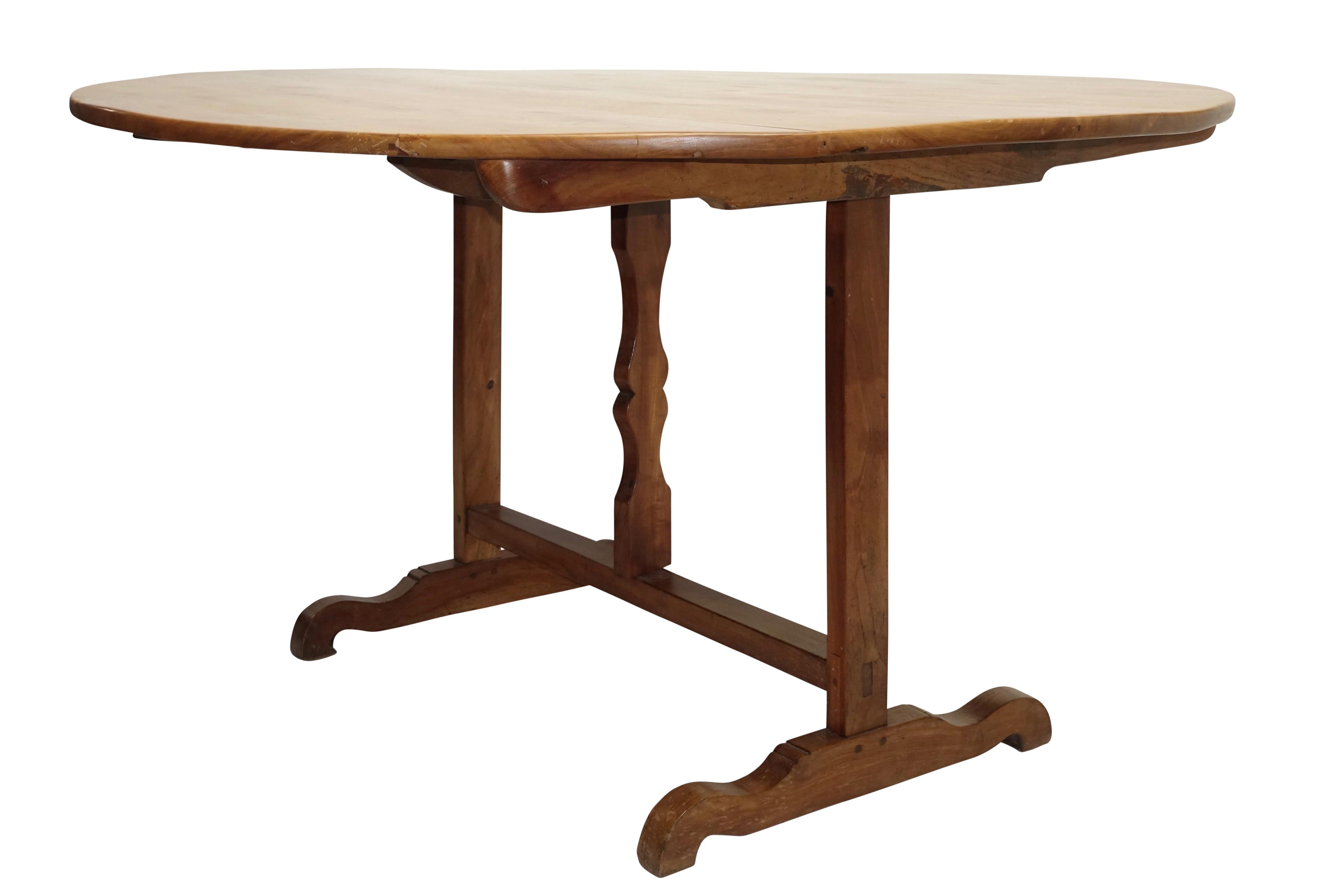 An unusual large round vendange bookspined cherrywood tilting wine tasting table with butterfly wedge support on a trestle base with cross bow feet, France, 19th century.