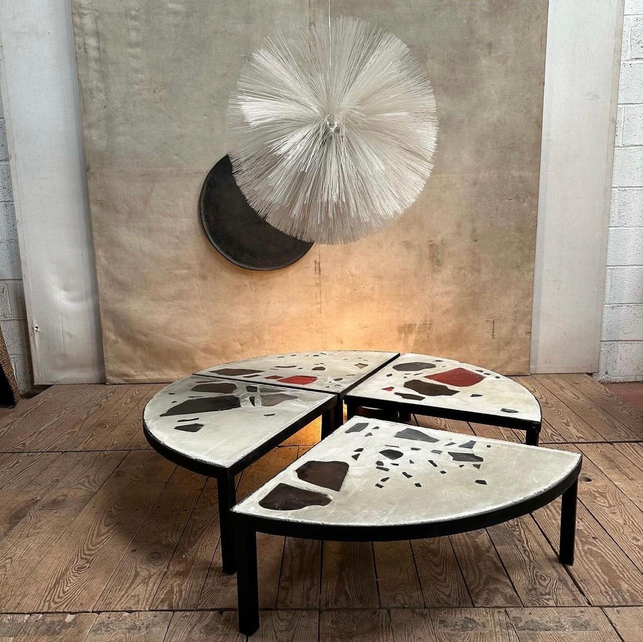 Une grande table basse ronde en béton avec élément en verre base en métal noir composée de quatre élément dans l'esprit de Jacues avoinet.