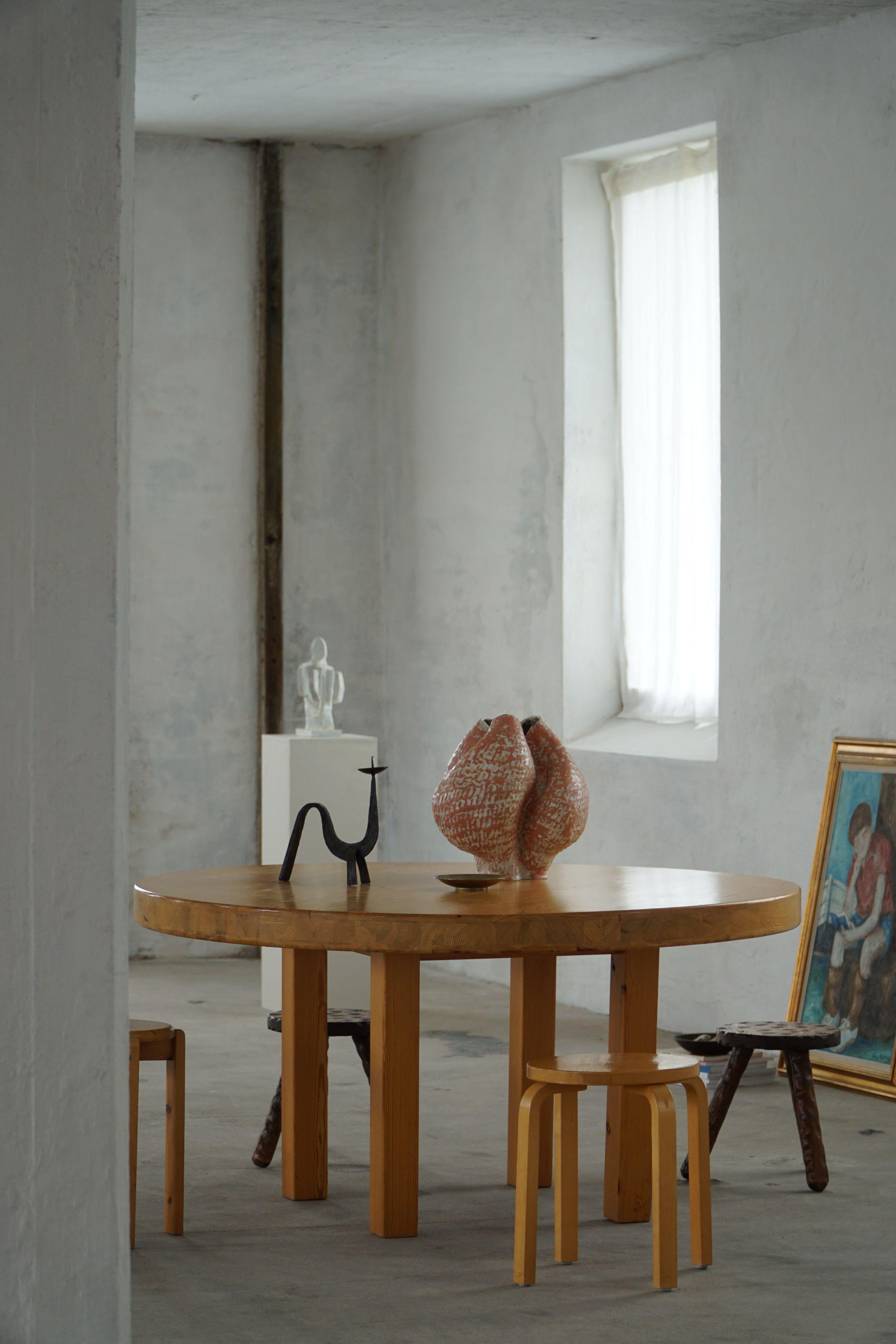 Questo imponente tavolo da pranzo rotondo, realizzato in pino massiccio, è un bellissimo esempio di artigianato scandinavo brutalista degli anni Settanta. Pur non essendo attribuito a un autore specifico, il design richiama il lavoro di Sven Larsson