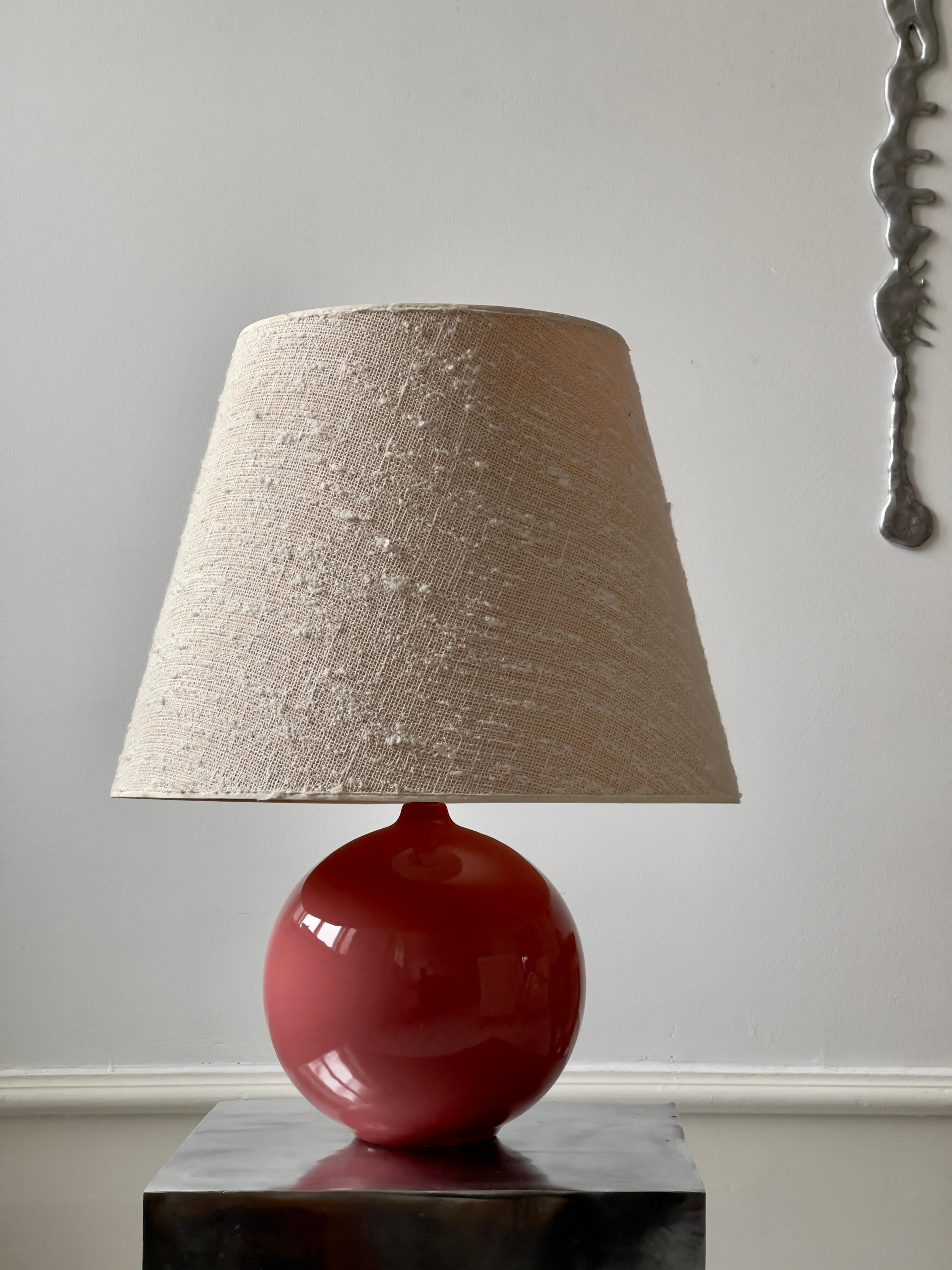 Large round mid-century french table lamp in rose red glazed porcelain. Elegant shape with an almost inflated feel to it. A sophisticated playful drop of color to the cool nordic interior perhaps. Very good condition.
(Rewired in off white fabric