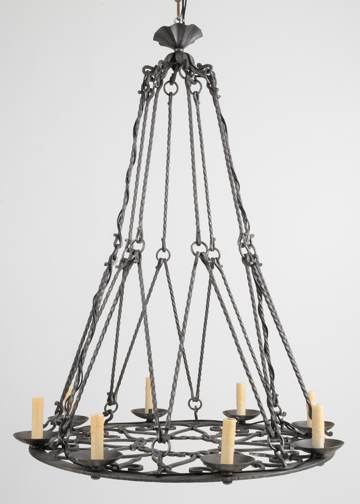 Large 19th century iron chandelier, electrified with eight lights and beeswax candle covers. The chandelier is made up of a circular base with heart and scroll detail suspended by twist and ring iron supports. Newly wired for US use.
The chandelier