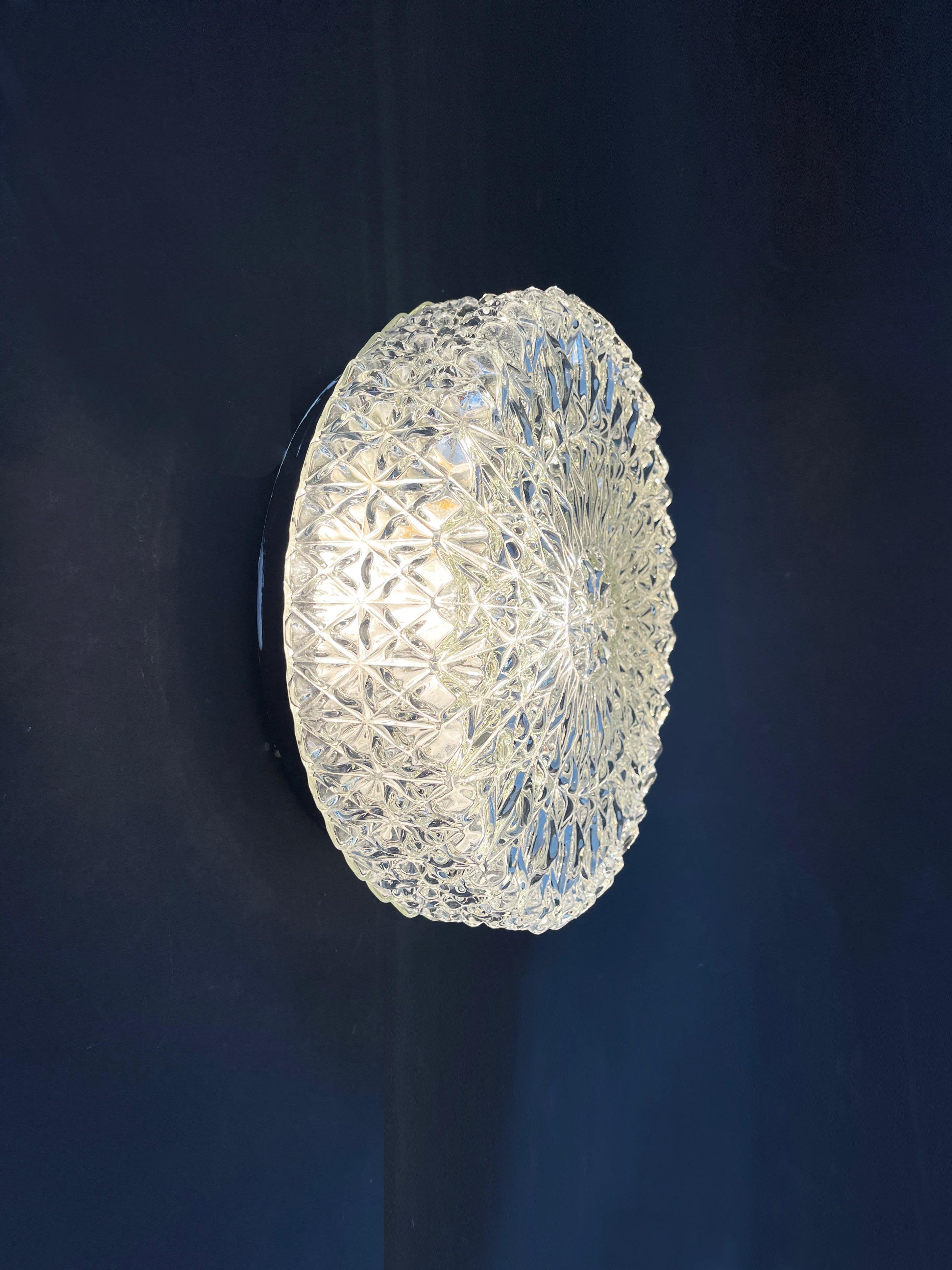 A beautiful large disc-like flush mount wall- or ceiling lamp by Honsel Leuchten, Germany. 
German classic of the 1960s to 70s.
The light shade is from chunky, ice crystal shaped colourless glass.
Gorgeously textured 3D glass, flush mount with metal