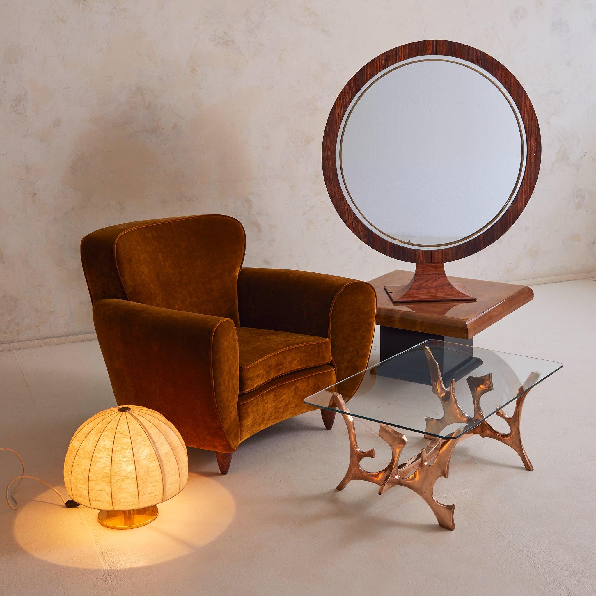 Miroir autoportant italien des années 1970, défini par sa présence sculpturale et ses matériaux exquis. Son large cadre circulaire est revêtu de bois de rose richement grainé, dont la chaleur est complétée par une fine incrustation de laiton qui