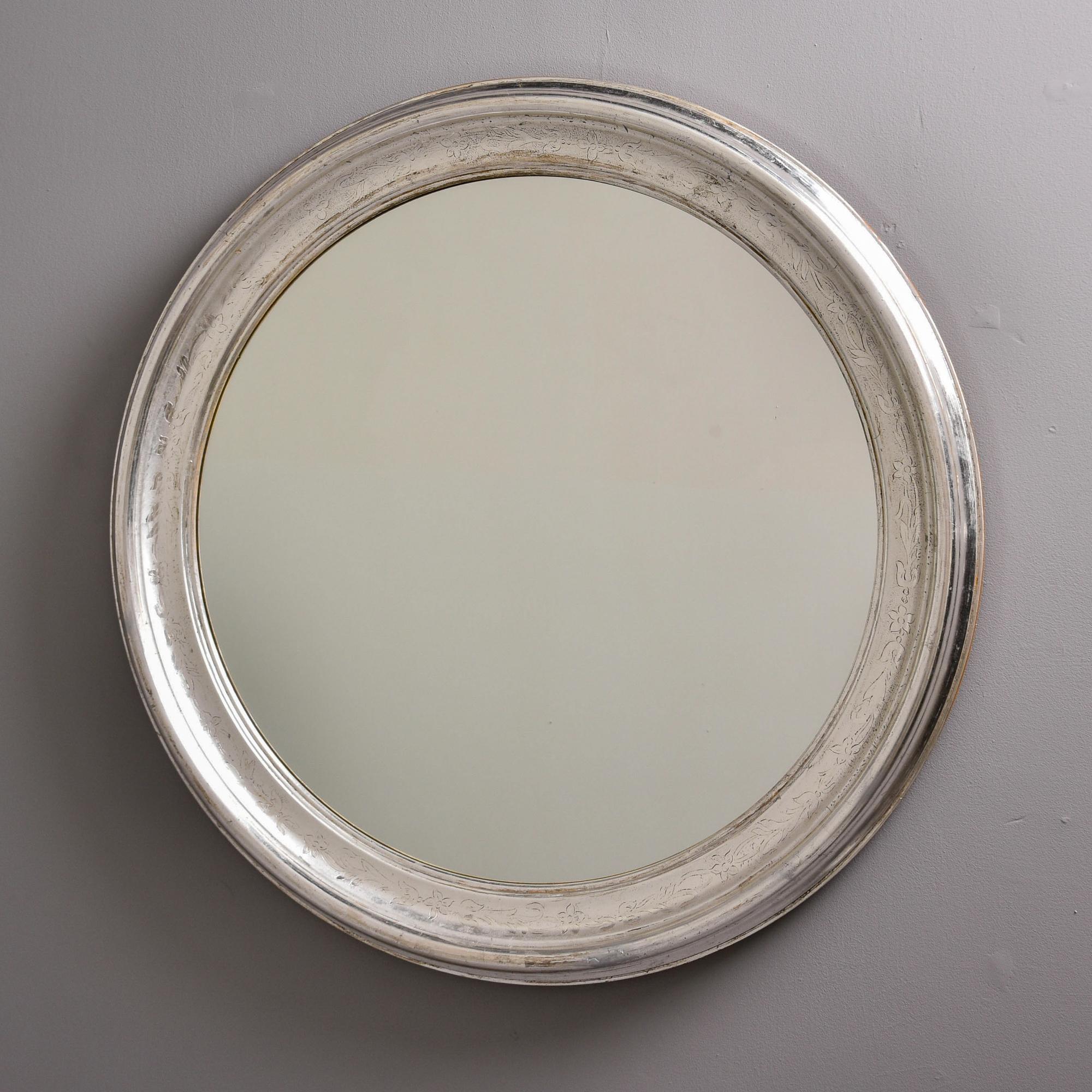 Found in France, this wood-framed silver leafed mirror dates from the 1960s or 70s. This round mirror has traditional Louis Philippe style elements with a silver leaf frame of wide moulding that has a subtle, etched design of a leafy vine on the top