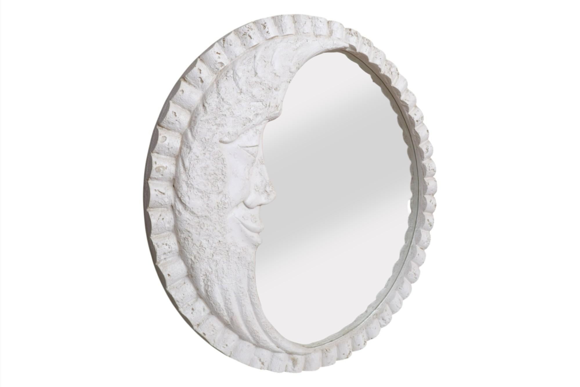 A large round embossed ‘Man In The Moon’ wall mirror. The plaster frame is scallop shaped with a simple happy face set in a waning crescent moon to the left. The frame is finished to give the look of natural stone.