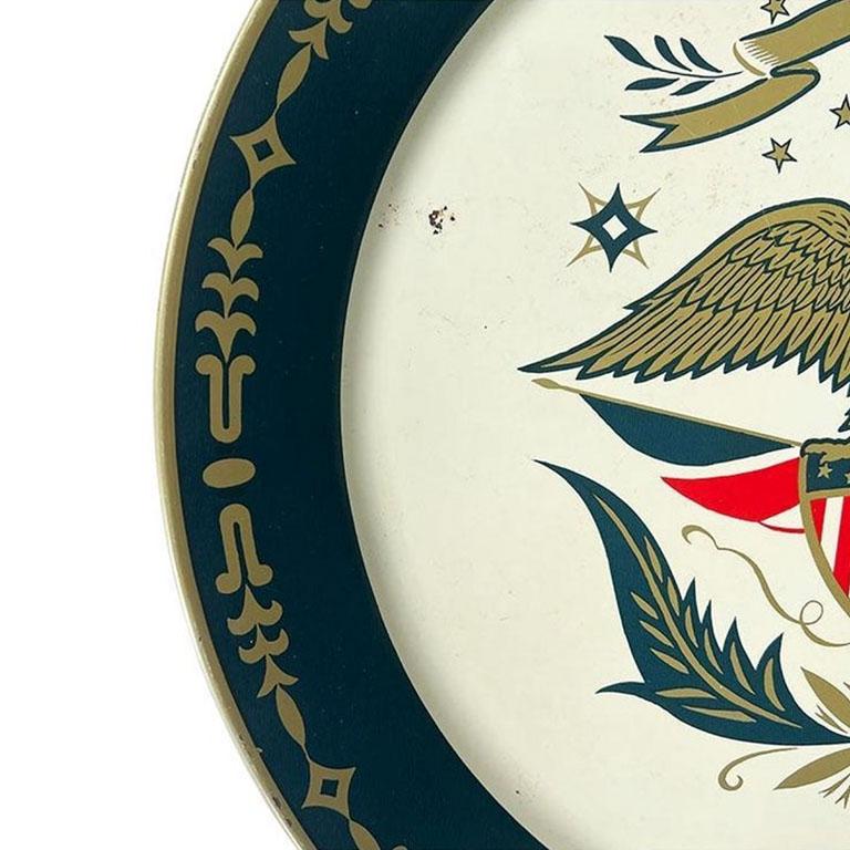 A very large round Americana metal serving tray. This piece will be great for serving drinks or hanging on a wall. It is created from metal and features an Americana Federal painted design. The center is painted cream, with a gold eagle at the