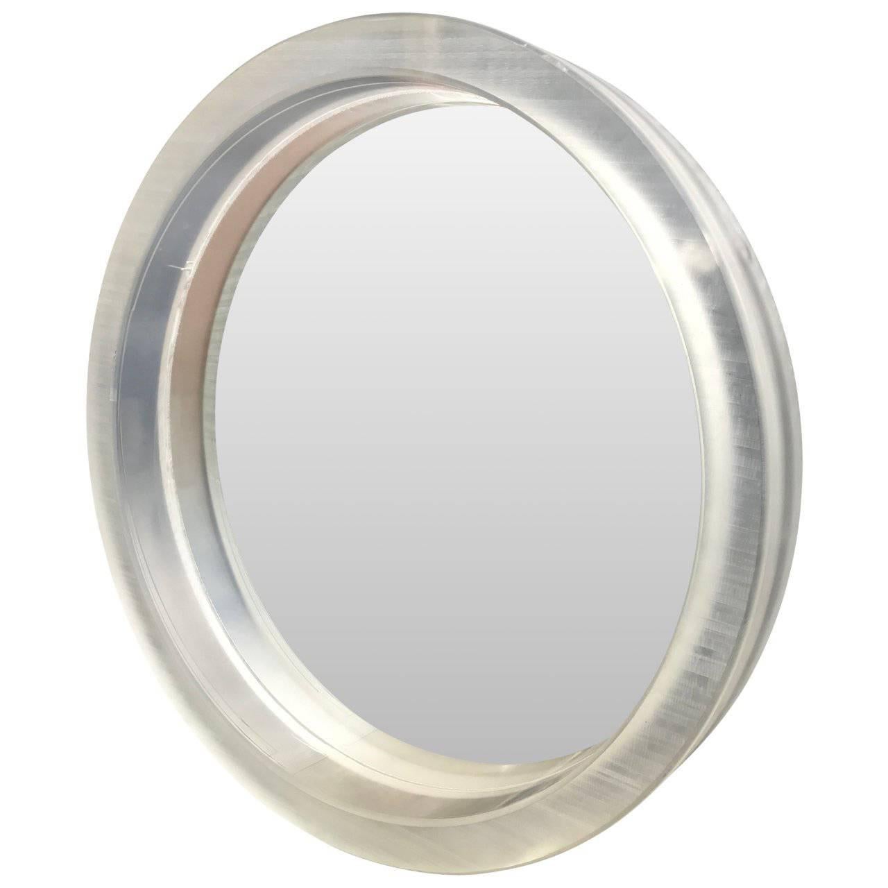 Large round Mid-Century Modern thick Lucite wall mirror

A single thick framed rough cut acrylic or Lucite mirror. The surface on the mirror is rough and individual, due their handcrafted cut. The mirror can be lit from behind in white or a