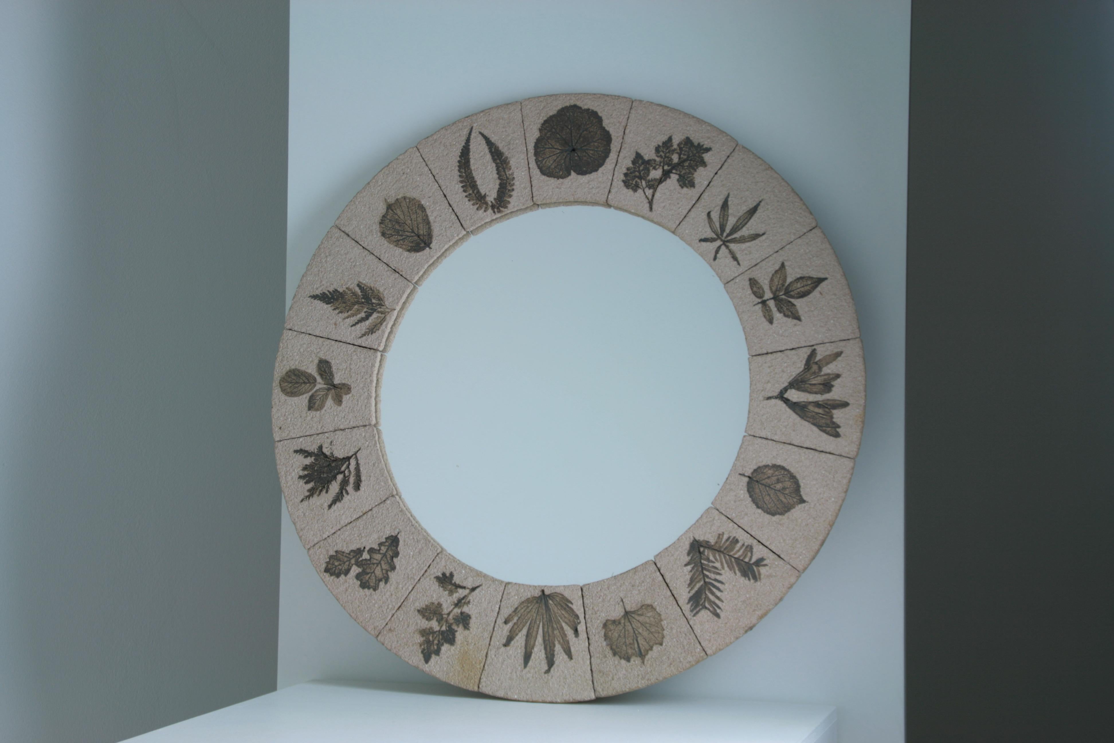 large round mirror with herbarium pattern from France and dating from the 1960s. the patterns are inlaid in pieces of reconstituted stone and forming the frame of the mirror. 

dimensions: diameter 56cm