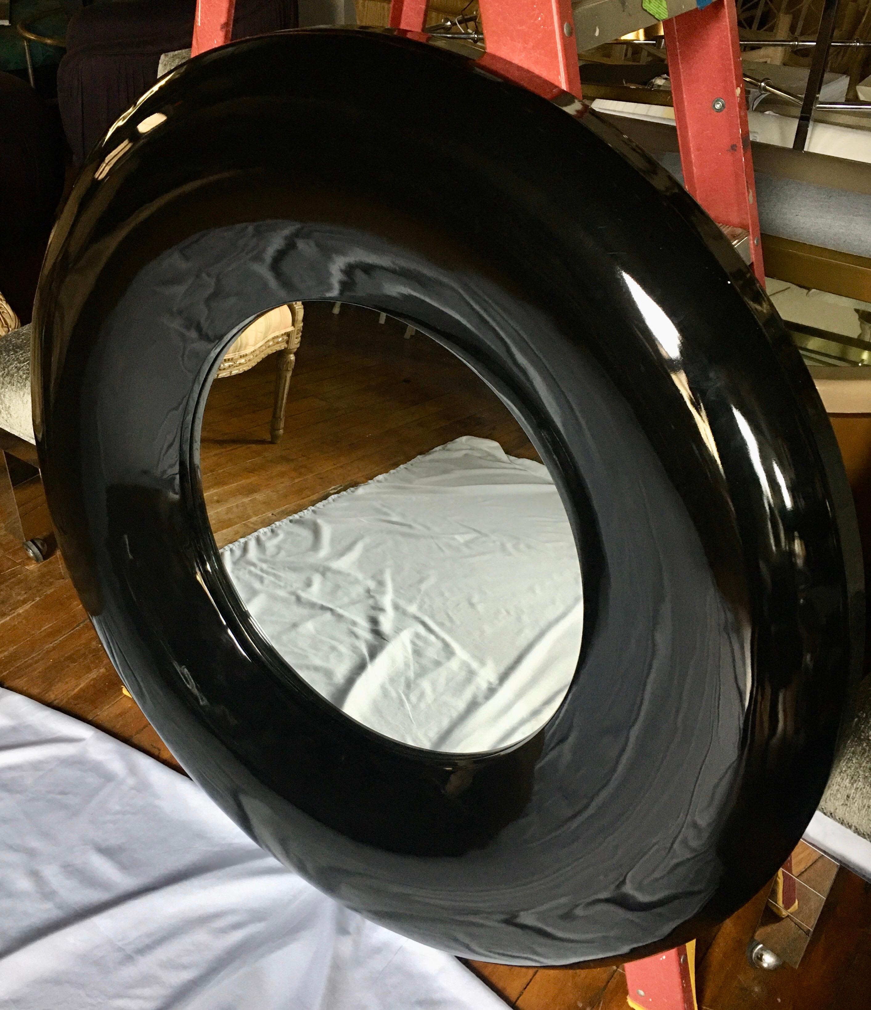 Large round modern bulls eye wall mirror featuring a glossy black lacquered finish.
Constructed of a lightweight molded composition material.